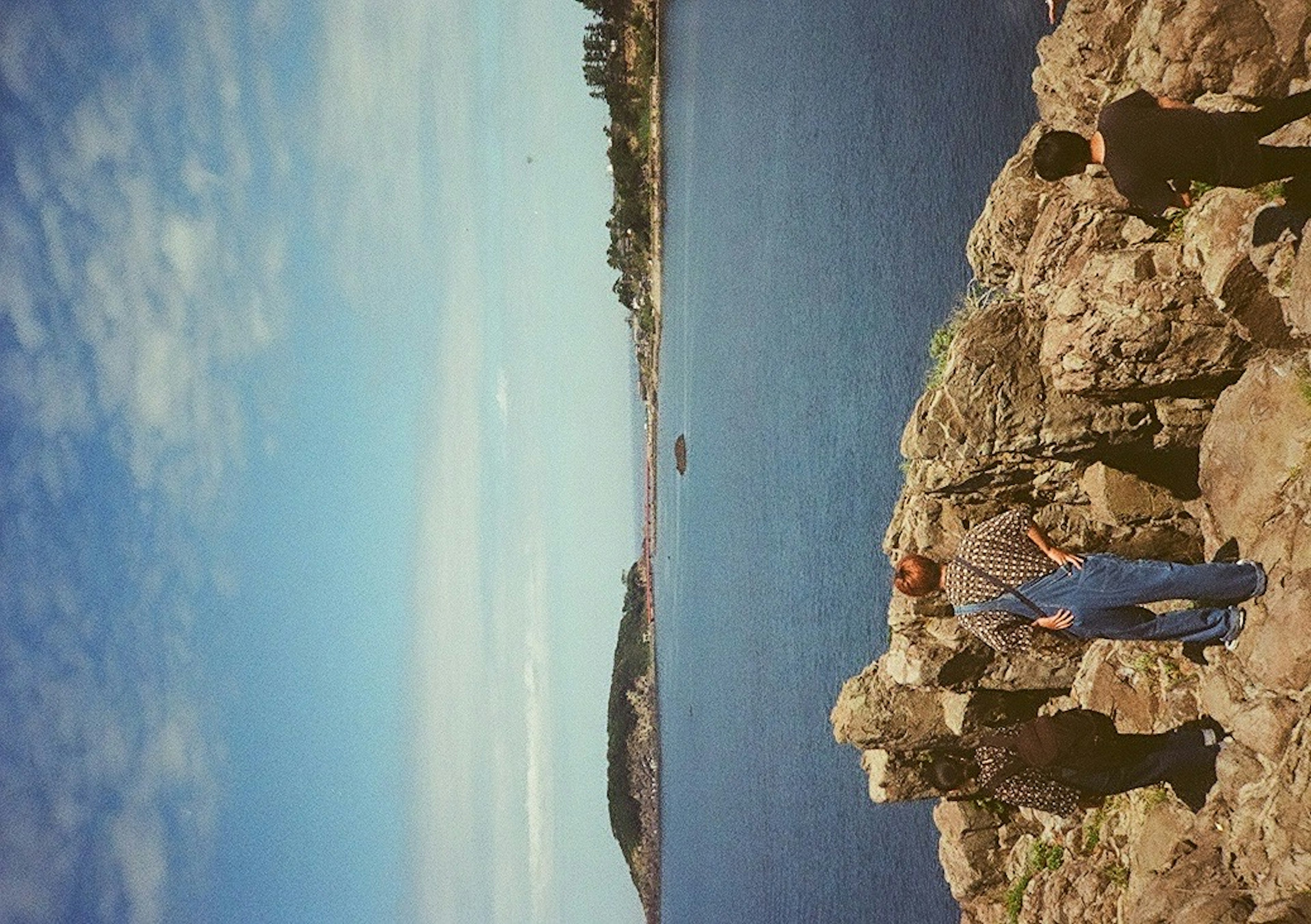 Uomo in piedi su rocce con vista sull'oceano sullo sfondo