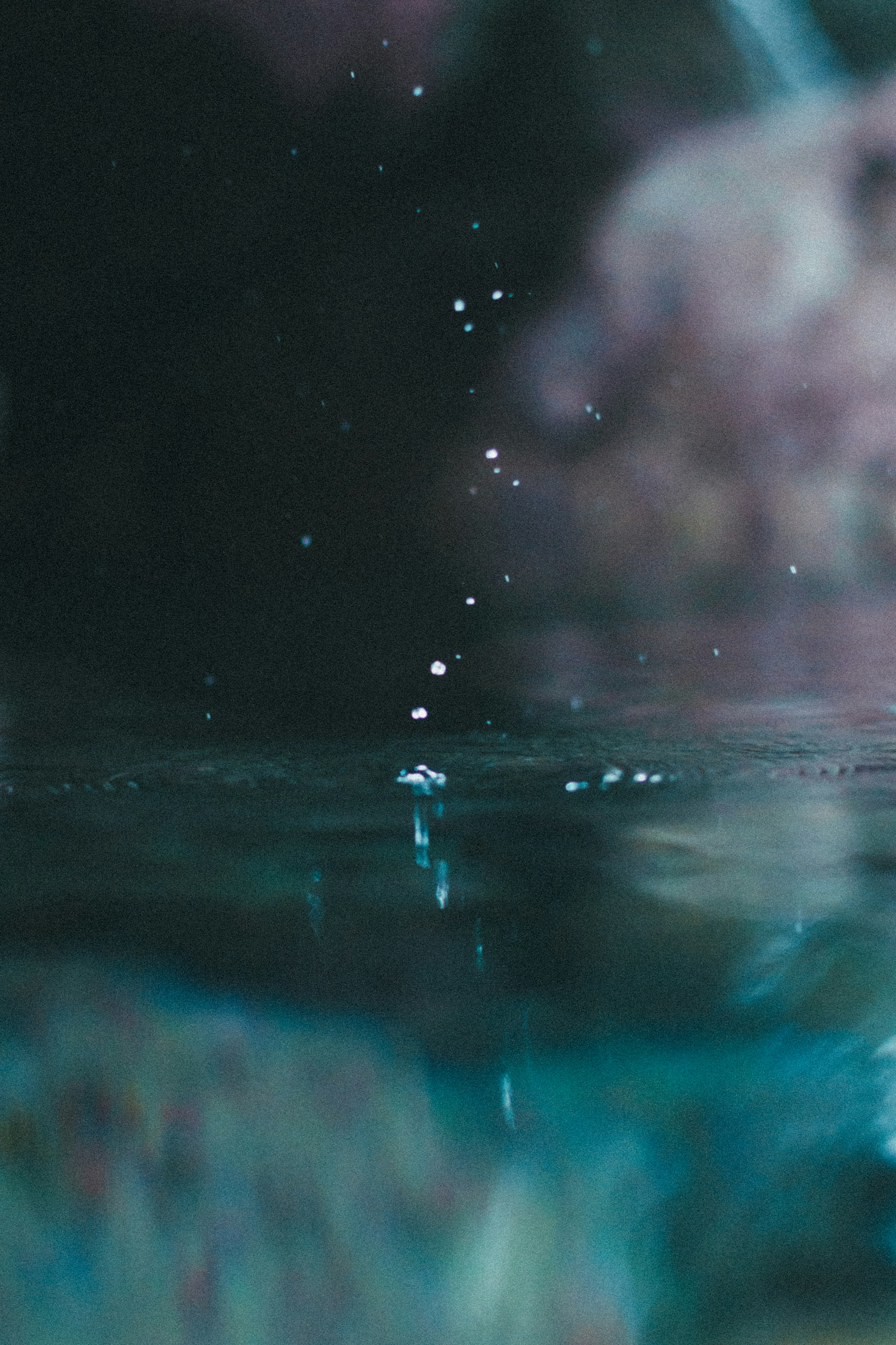 Nahaufnahme von Wassertropfen, die auf eine Oberfläche mit blauem Hintergrund fallen