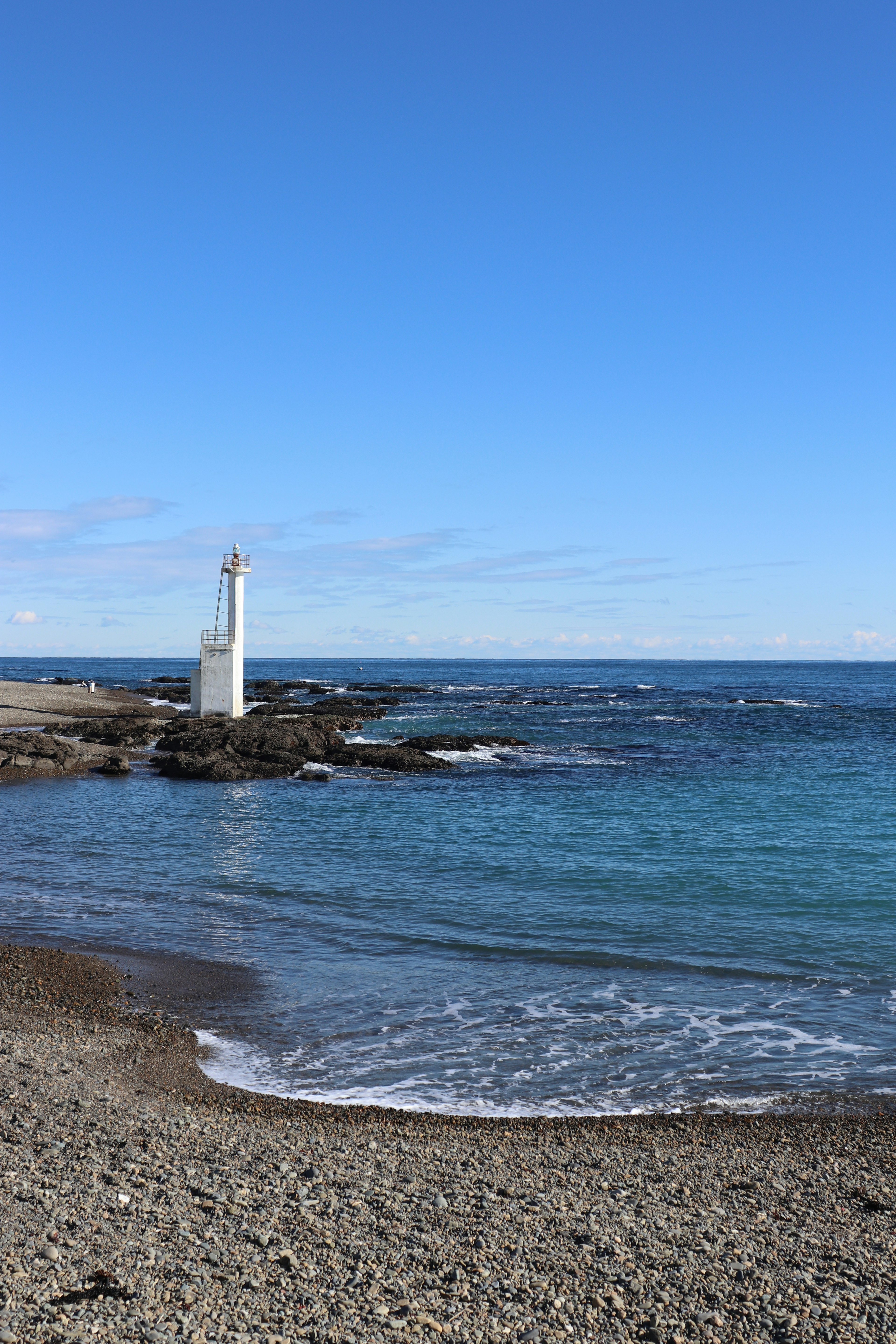 Malersicher Blick auf einen Leuchtturm am blauen Meer unter einem hellen Himmel