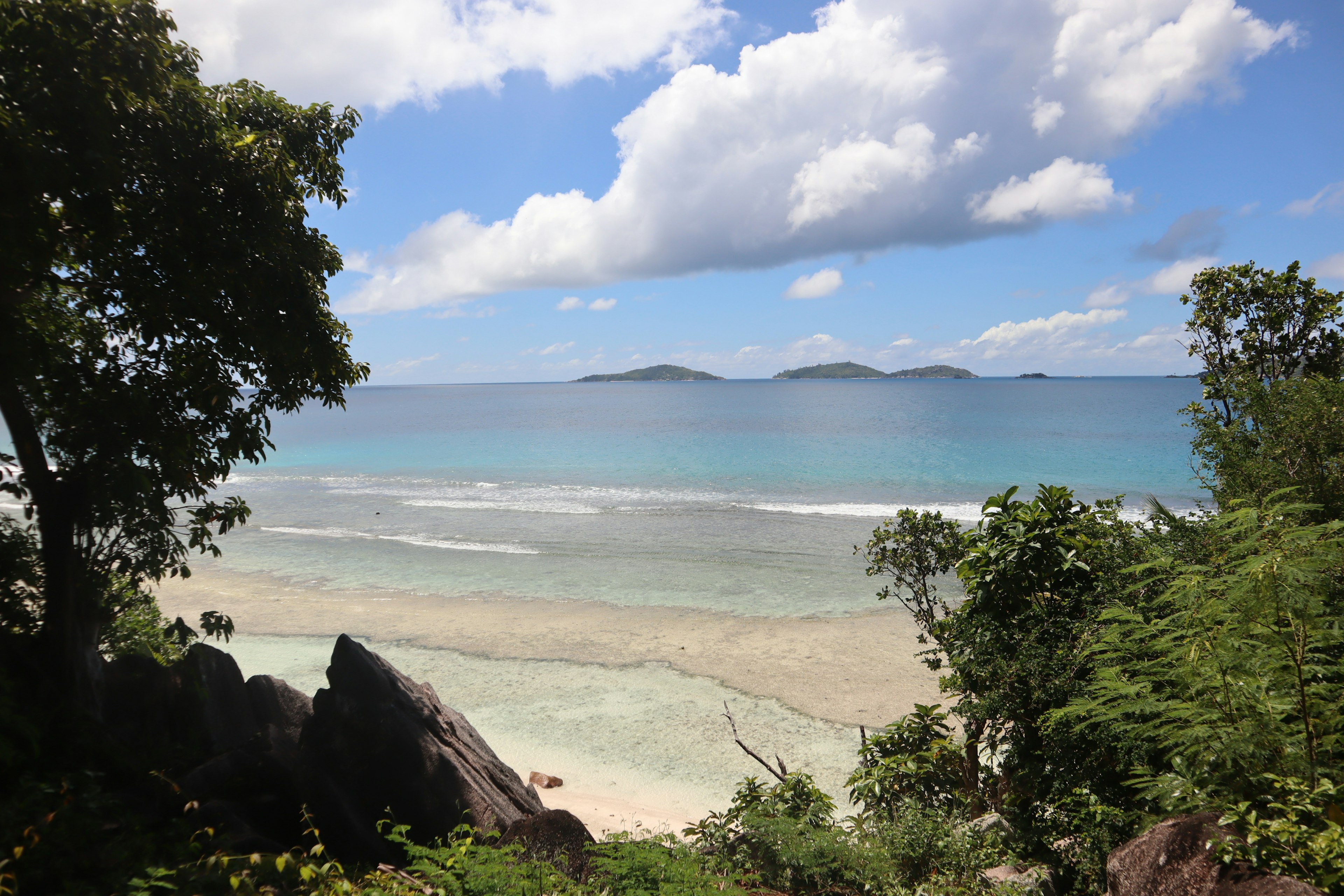 Scenic view of blue ocean and white sandy beach with distant islands