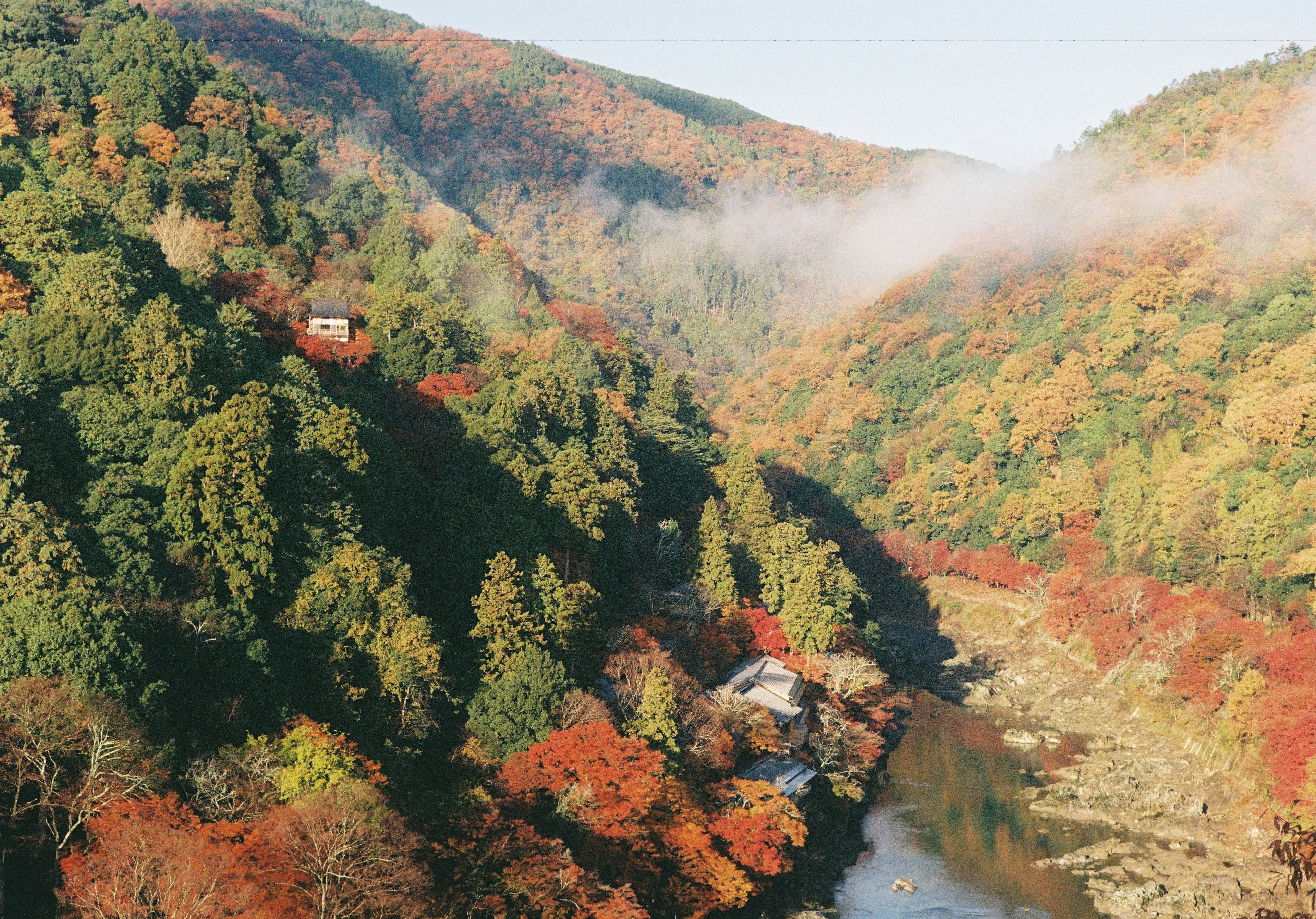 Landschaftliche Ansicht von Bergen und Fluss mit herbstlichem Laub