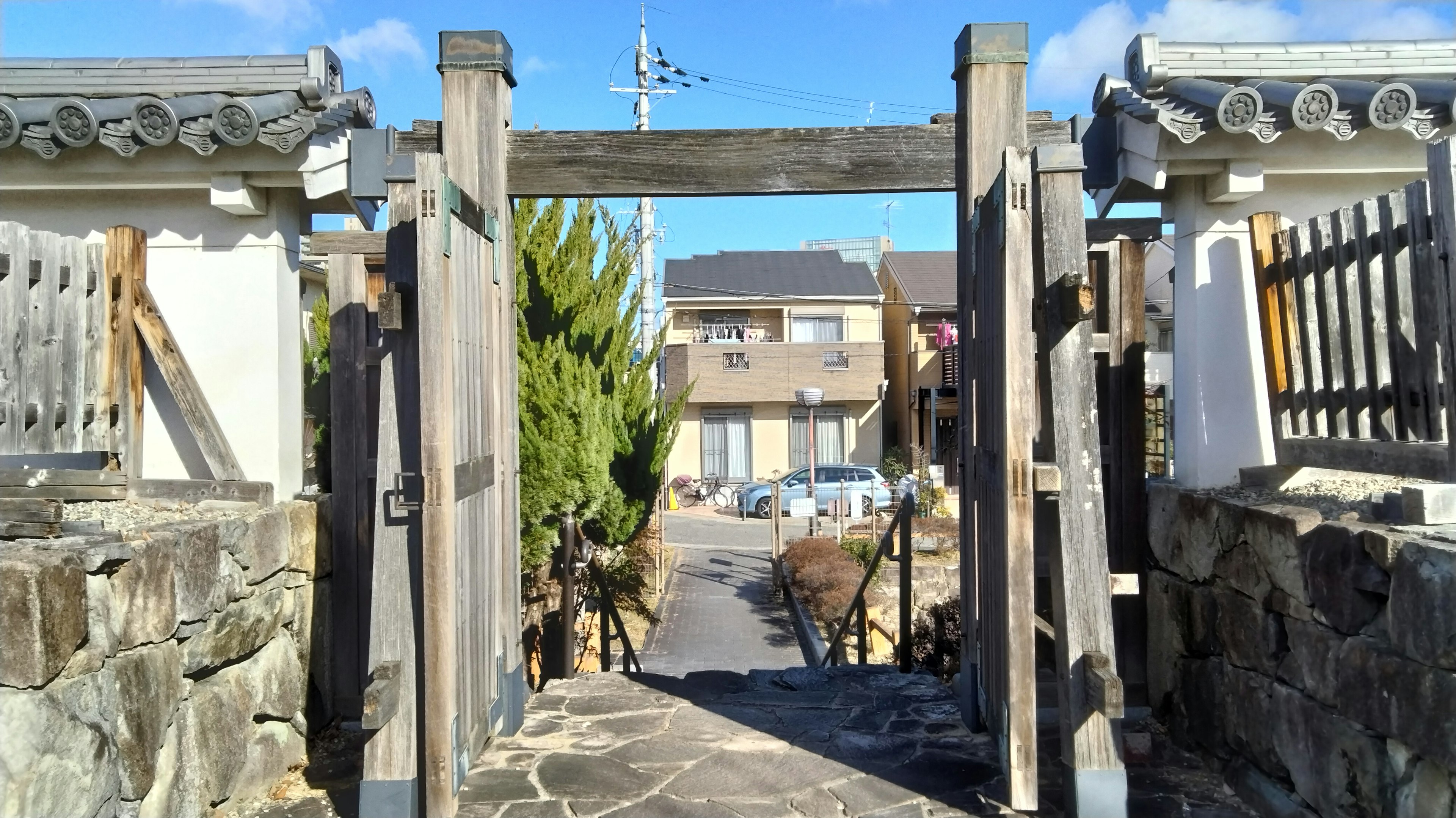 Entrée d'un jardin japonais avec une porte en bois et un chemin en pierre