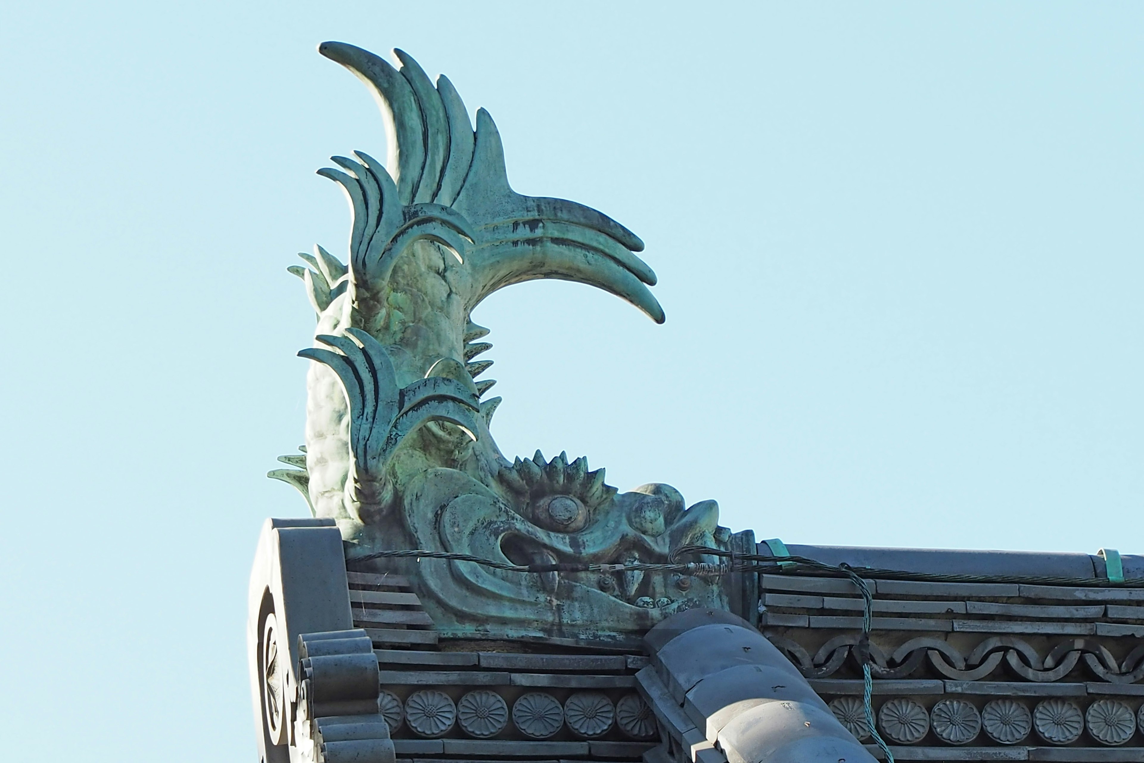 Green decorative sculpture on a rooftop resembling a bird with intricate design