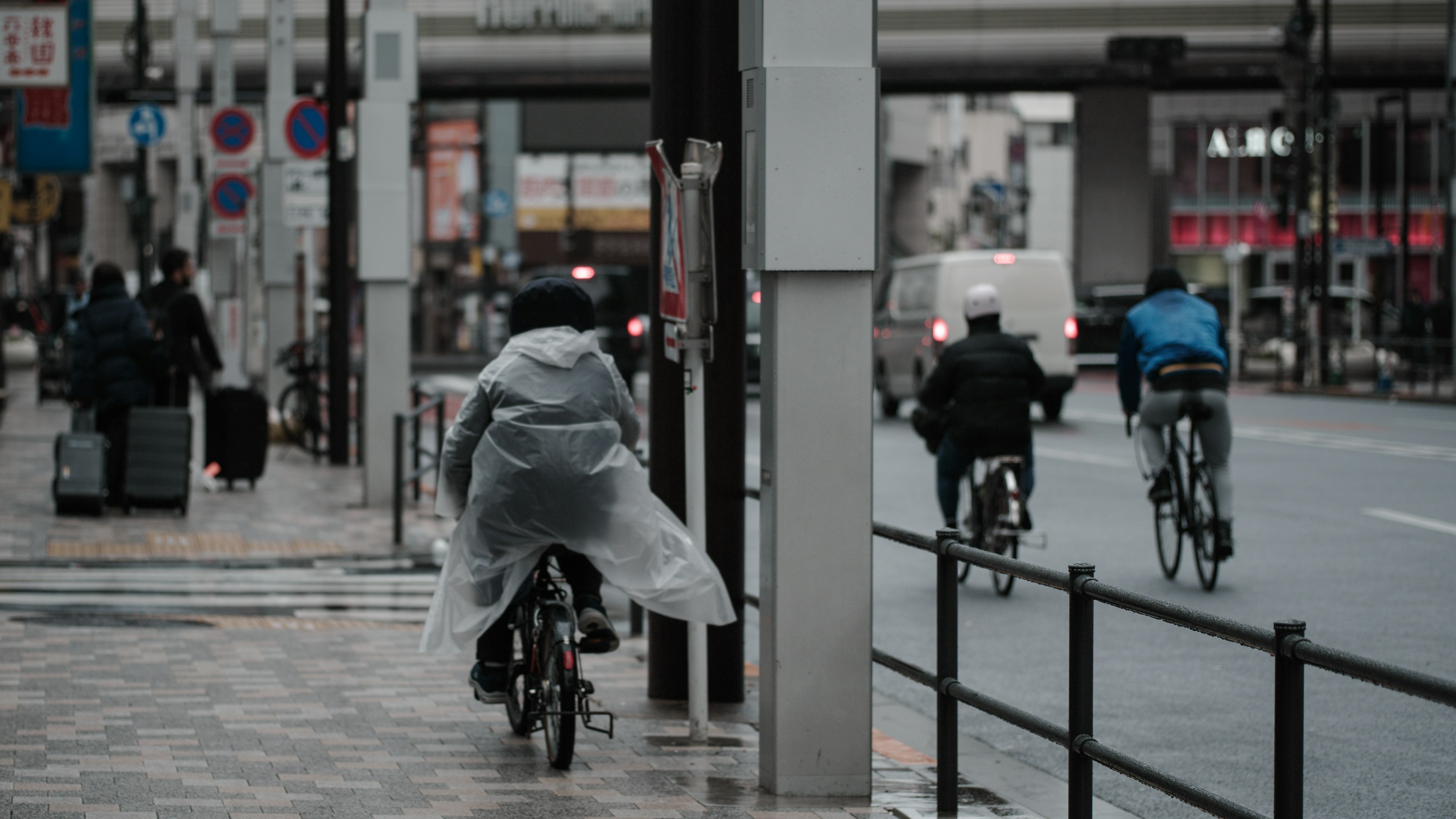 ผู้คนขี่จักรยานในฝนพร้อมทิวทัศน์ในเมือง