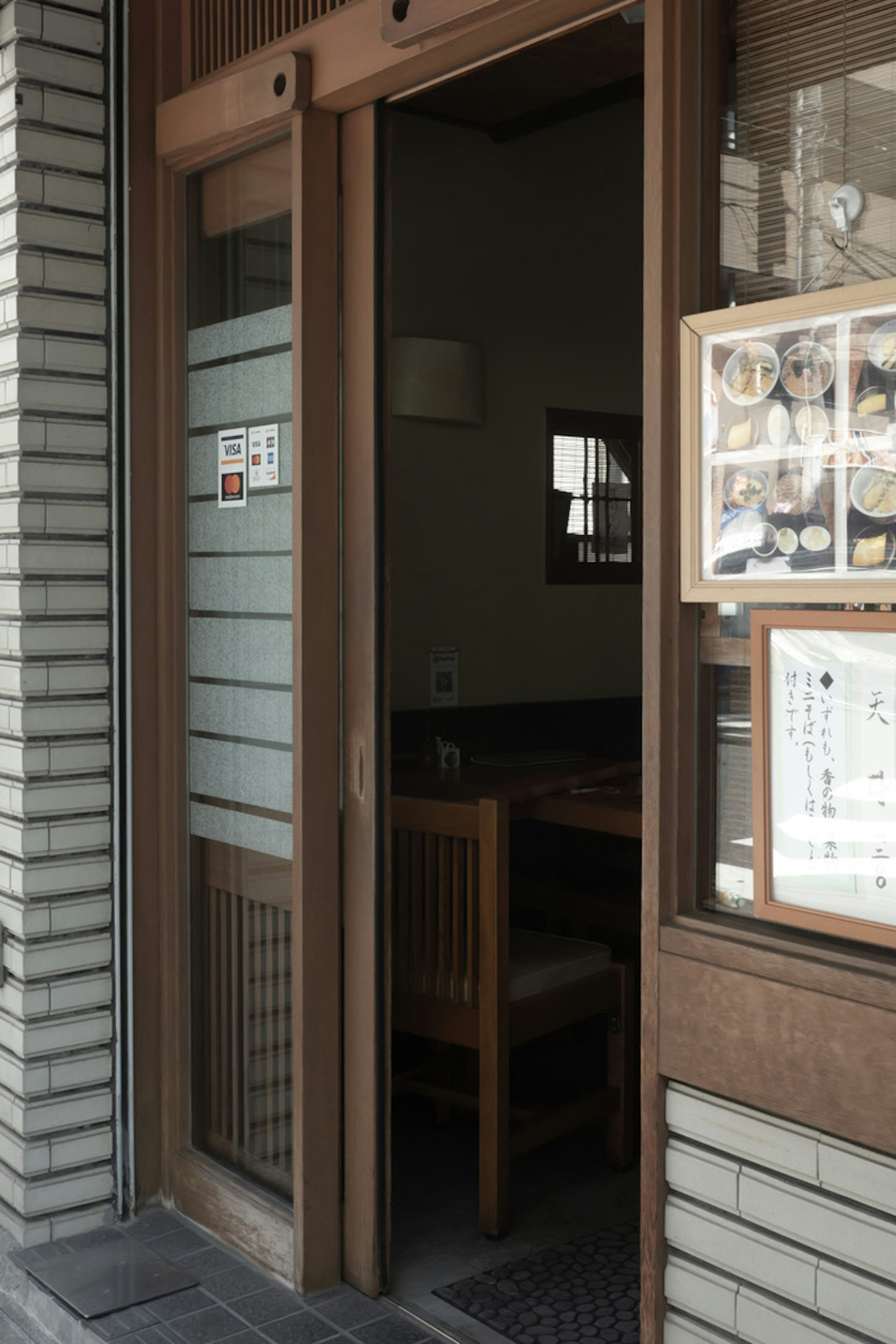 Restaurant entrance with an open wooden door visible table and chairs inside