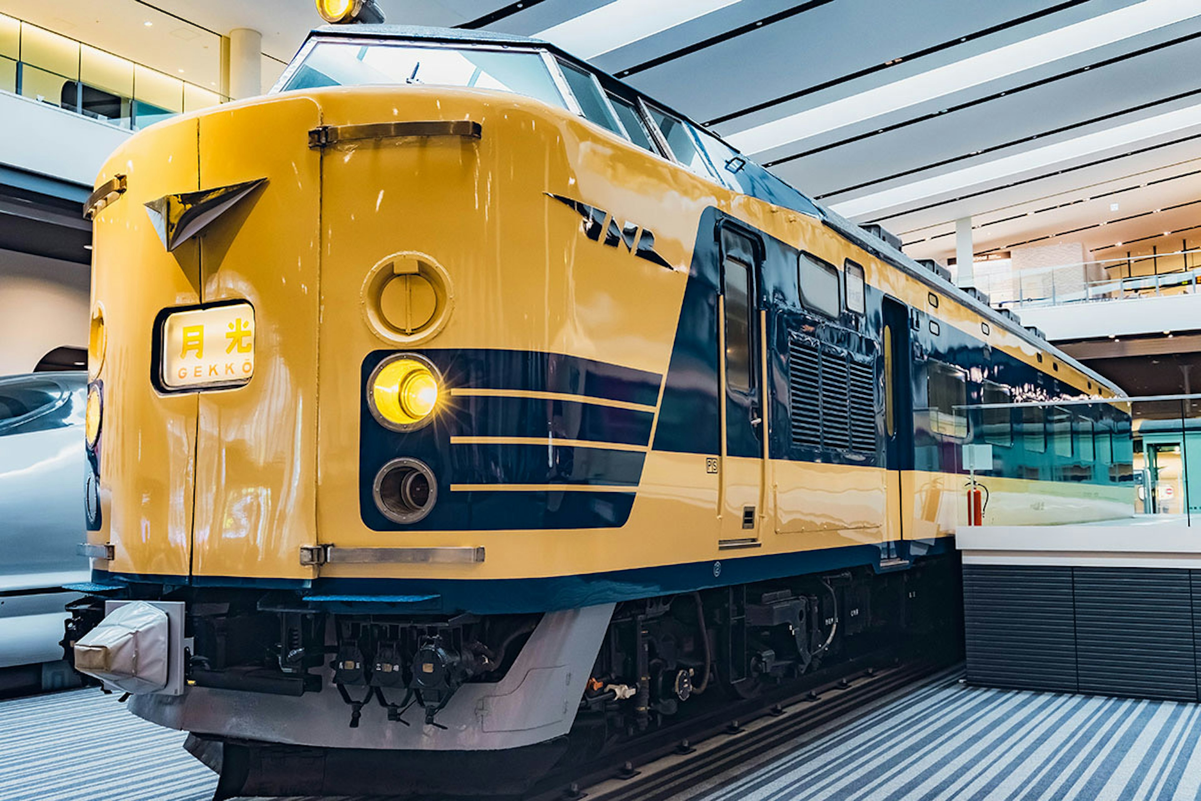 A yellow and blue train displayed in a modern interior space