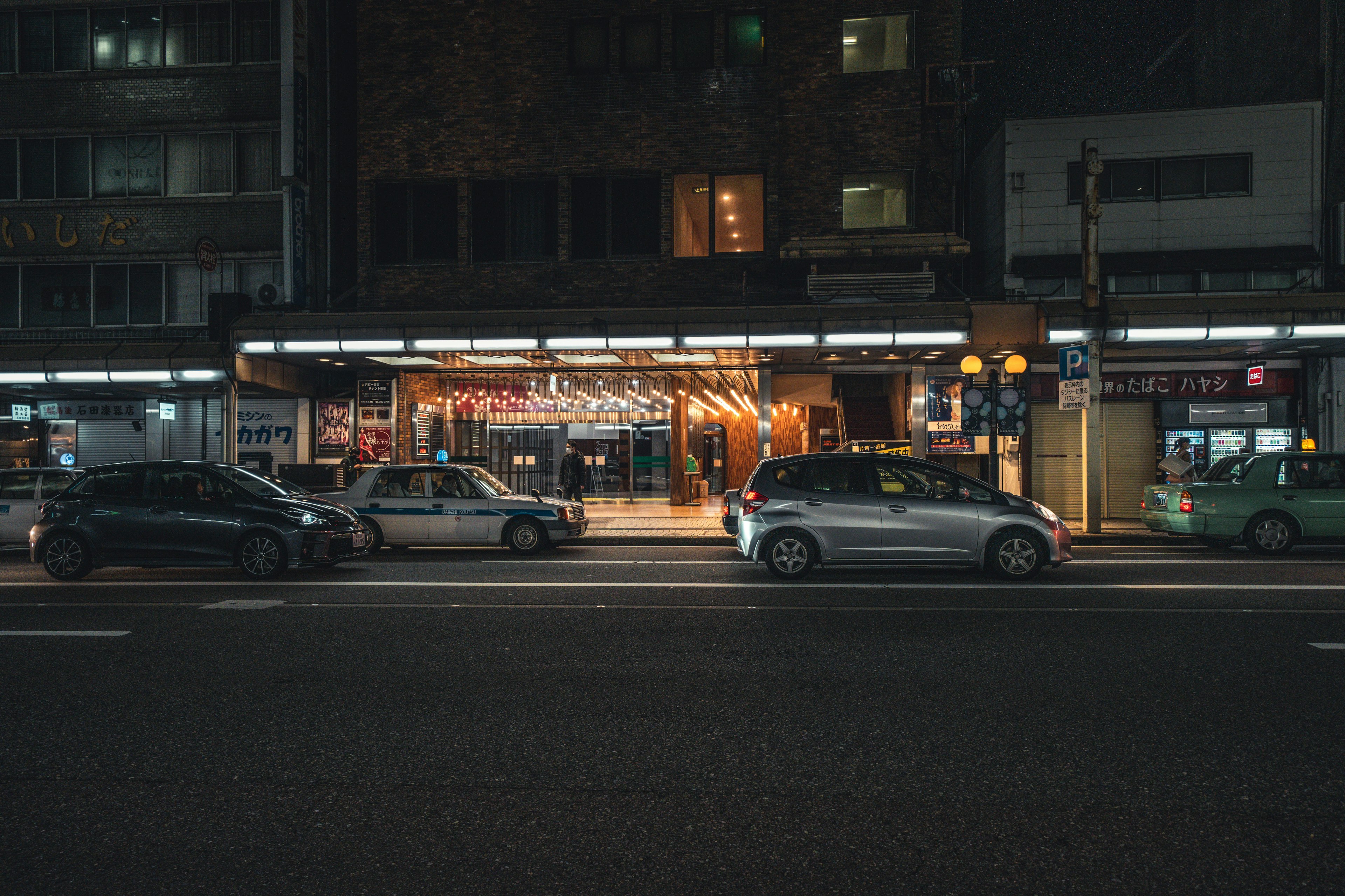 Außenansicht eines Geschäfts bei Nacht mit geparkten Autos auf der Straße