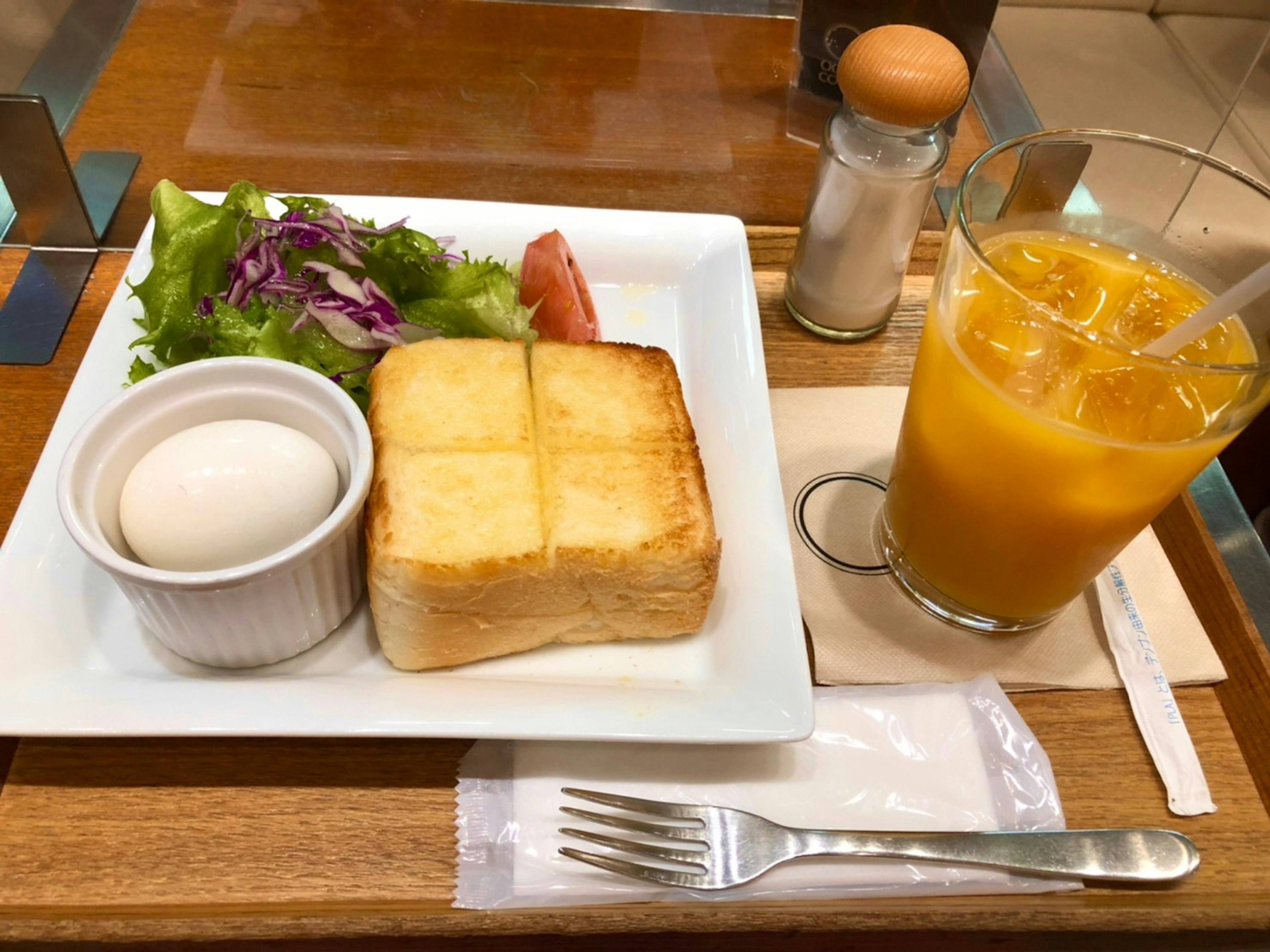 Breakfast plate featuring toast salad boiled egg and orange juice