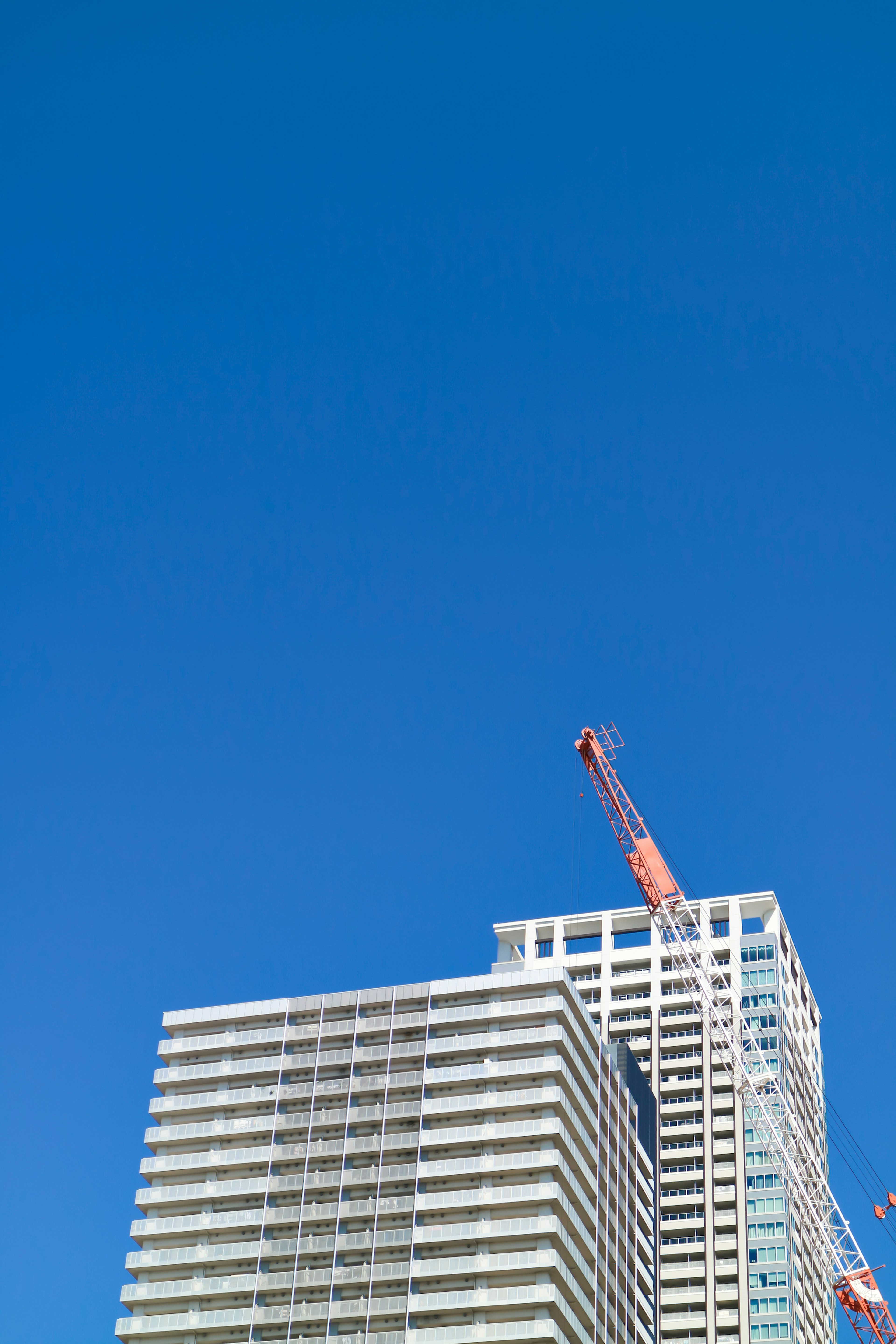 Teil eines Hochhauses mit einem Kran unter einem klaren blauen Himmel