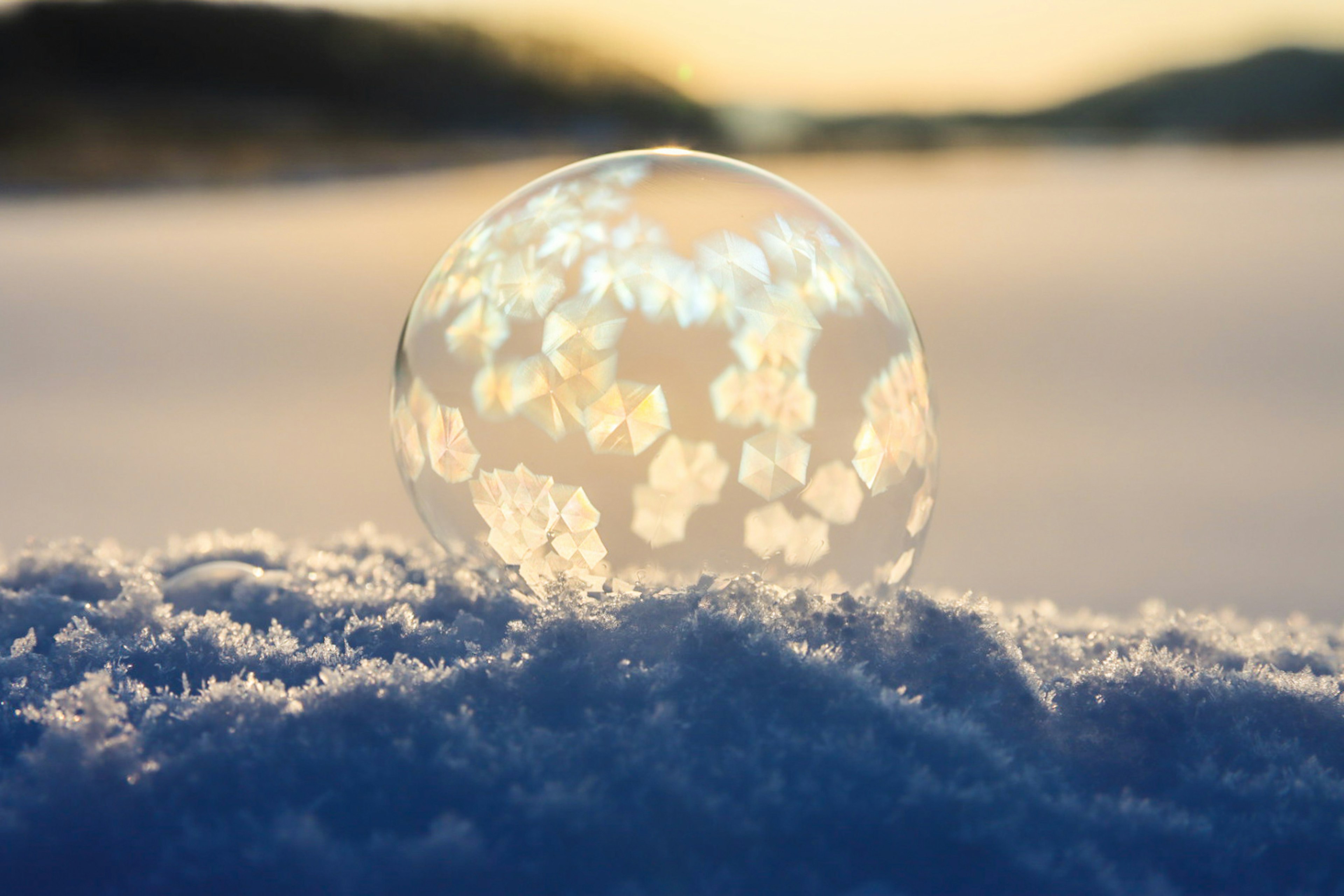 Bolla di ghiaccio appoggiata sulla neve con paesaggio invernale sullo sfondo