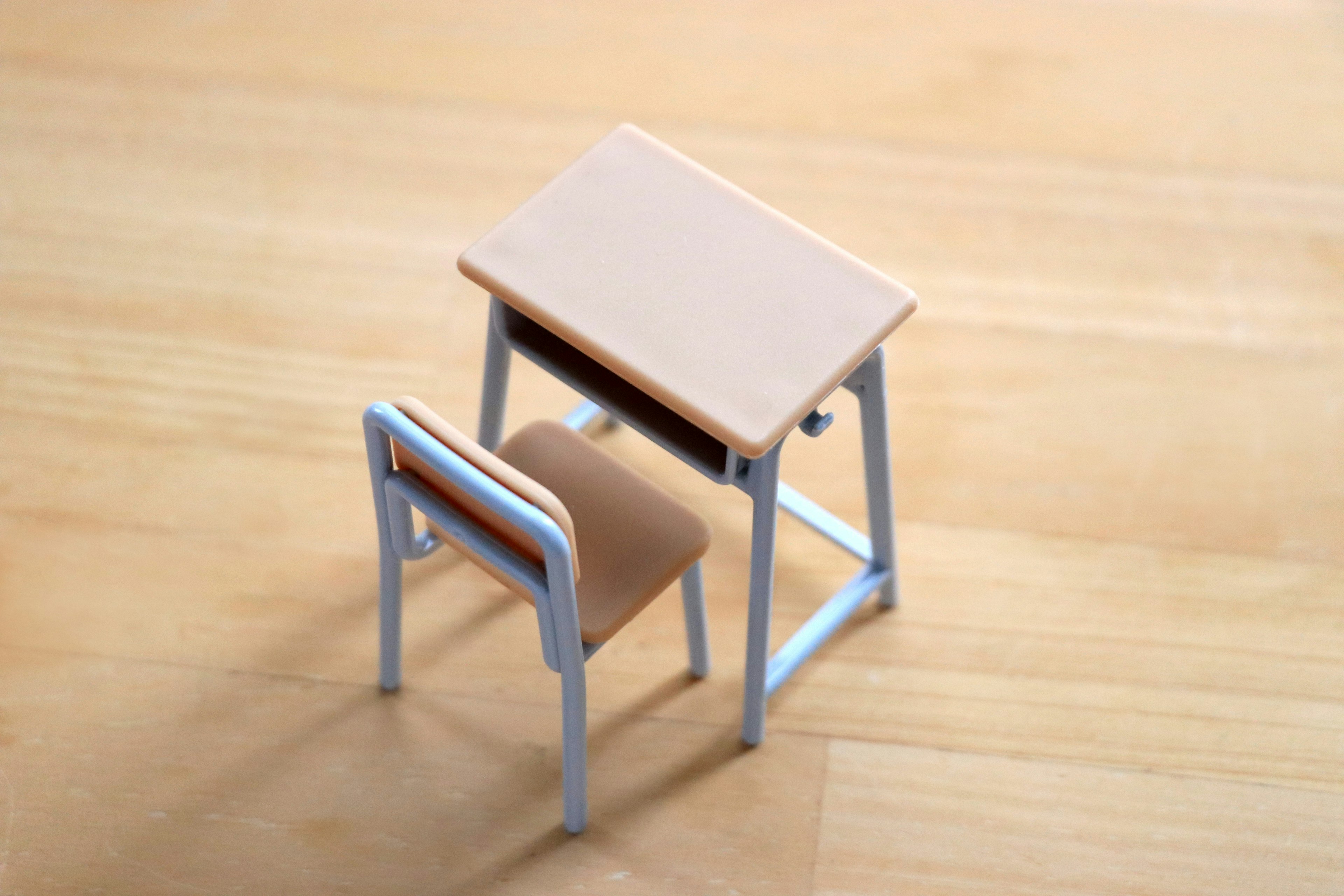 Un modelo en miniatura de escritorio y silla colocado sobre un suelo de madera