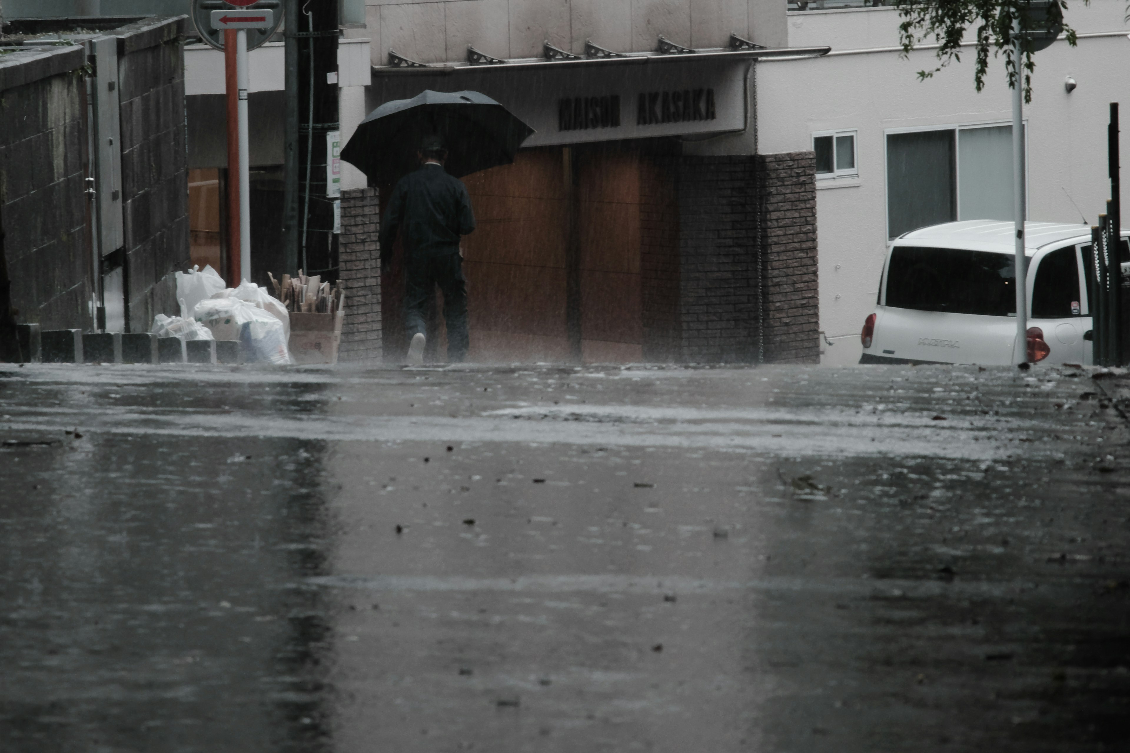 雨の中で傘を持った人が立っている街の風景