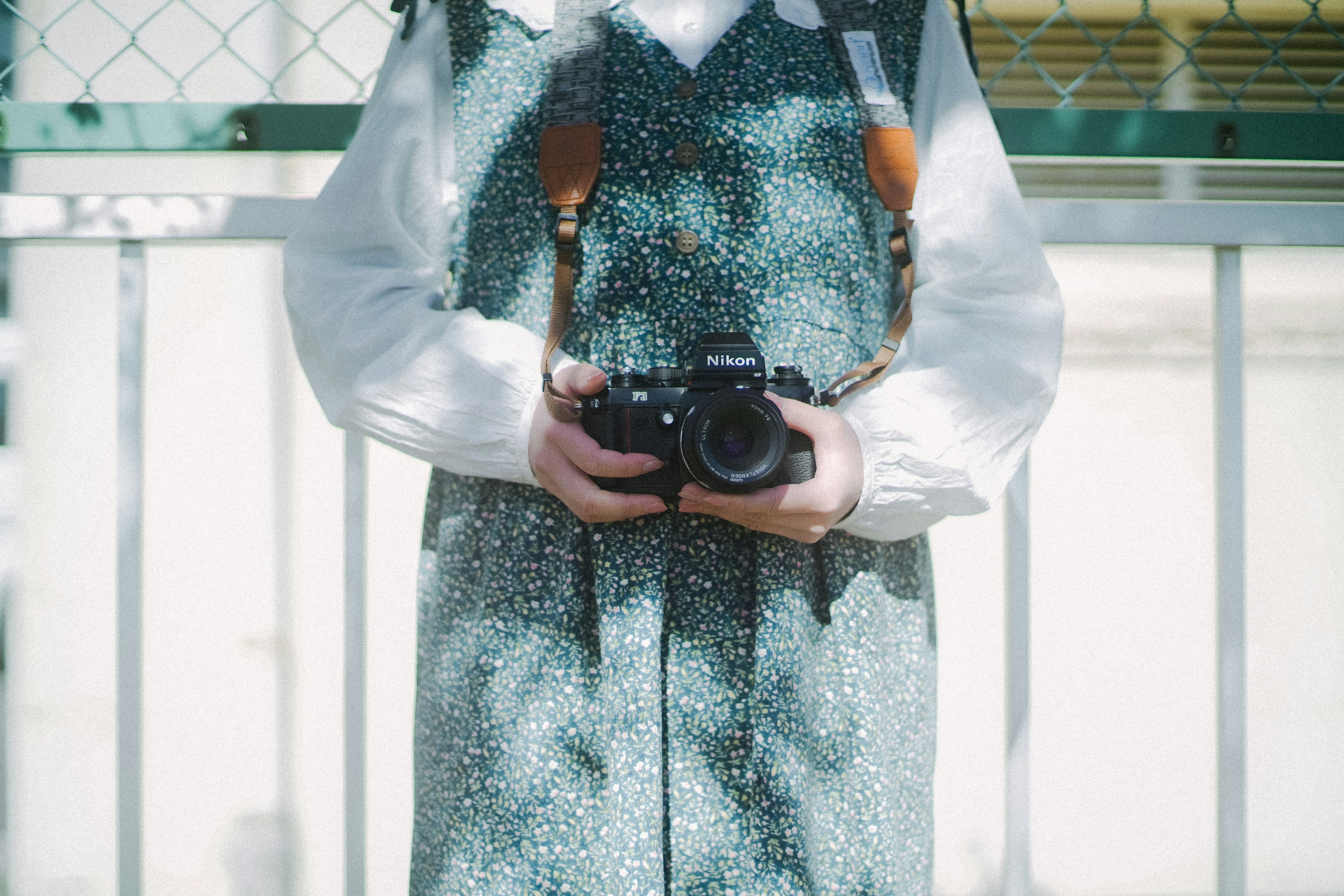 Person holding a camera wearing a green polka dot dress