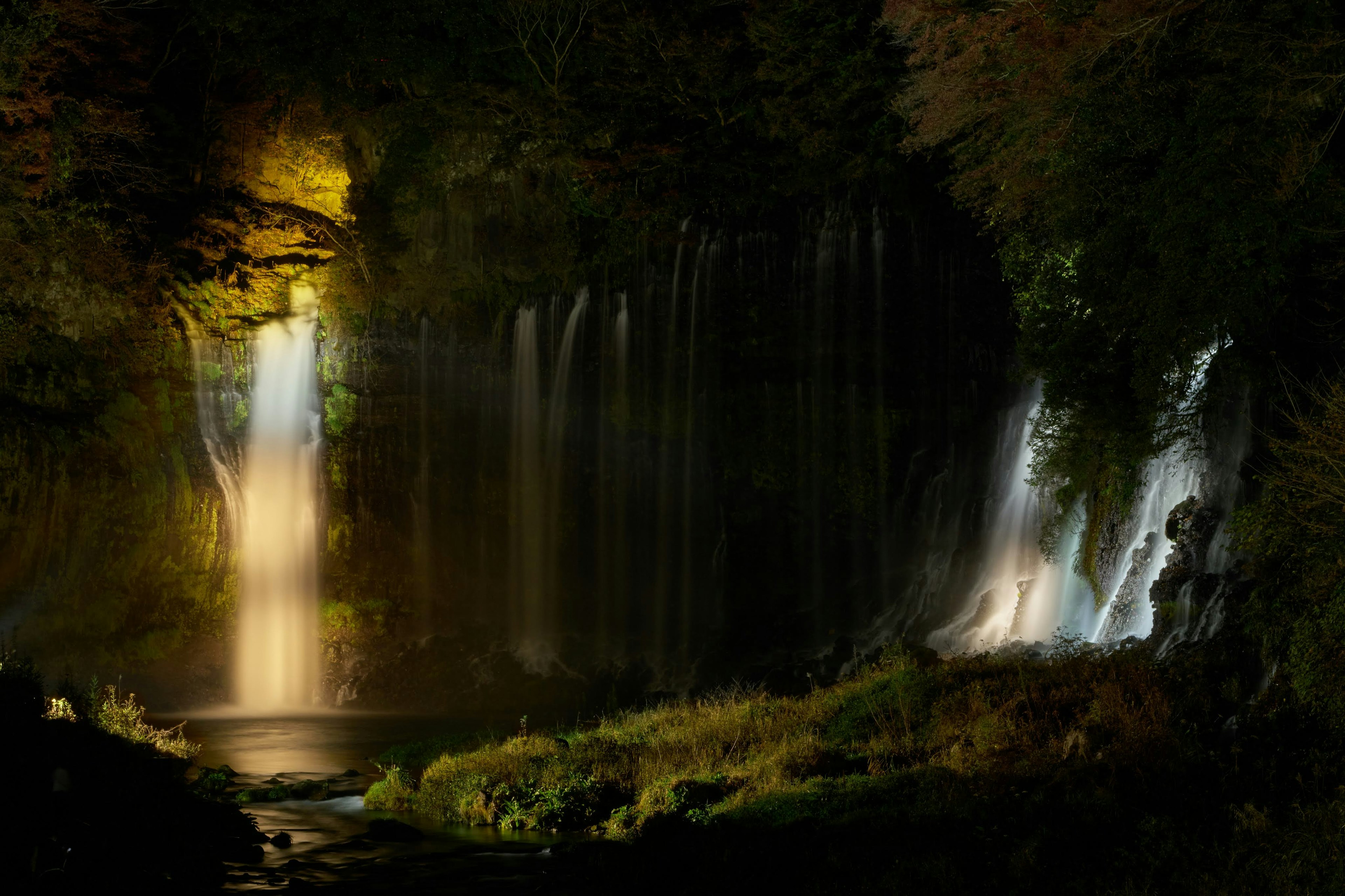 Une belle scène de cascade illuminée dans l'obscurité l'eau s'écoulant gracieusement la lumière brillant sur les chutes