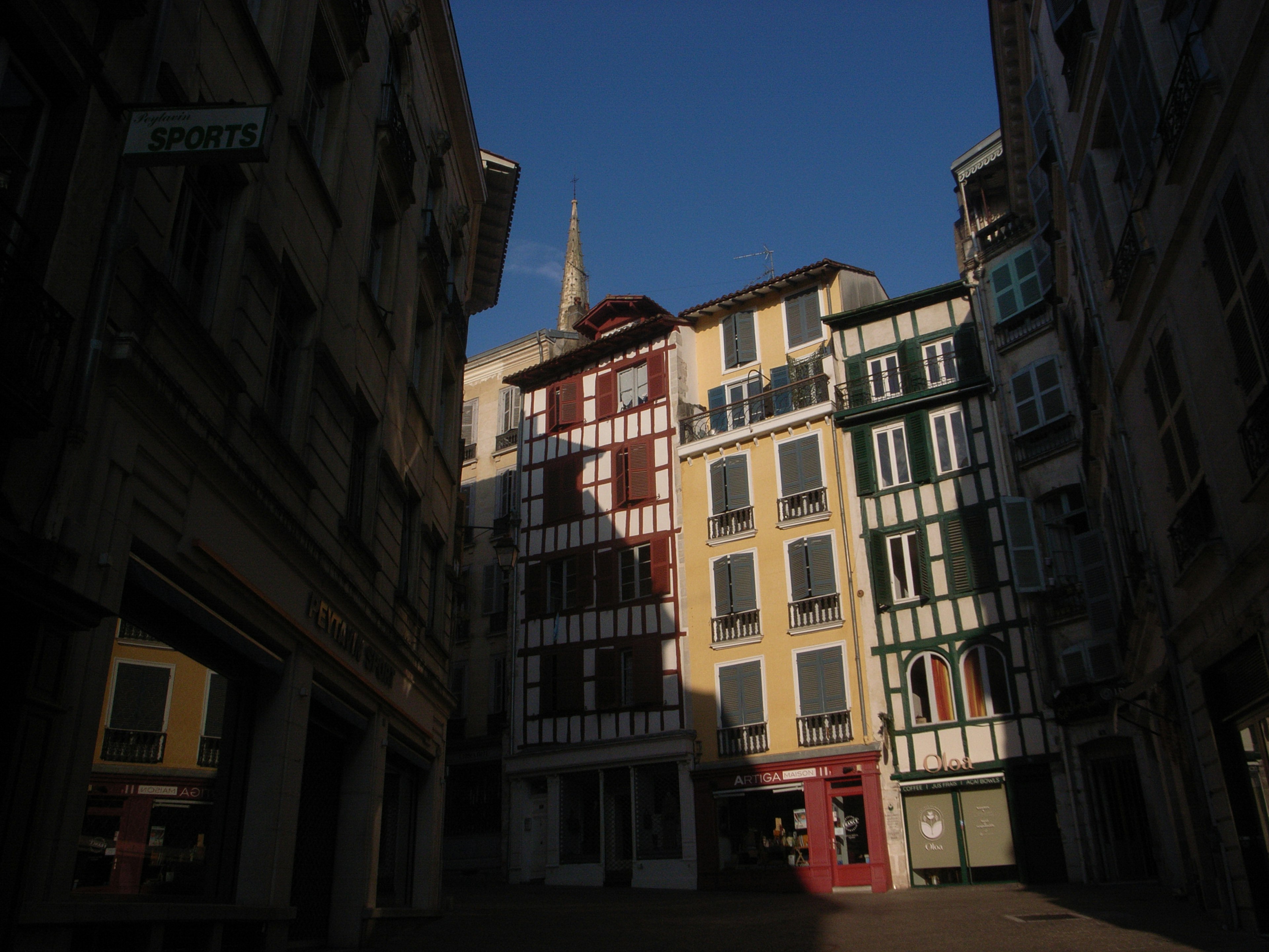 Strada stretta fiancheggiata da edifici storici a Bayonne con facciate colorate e ombre