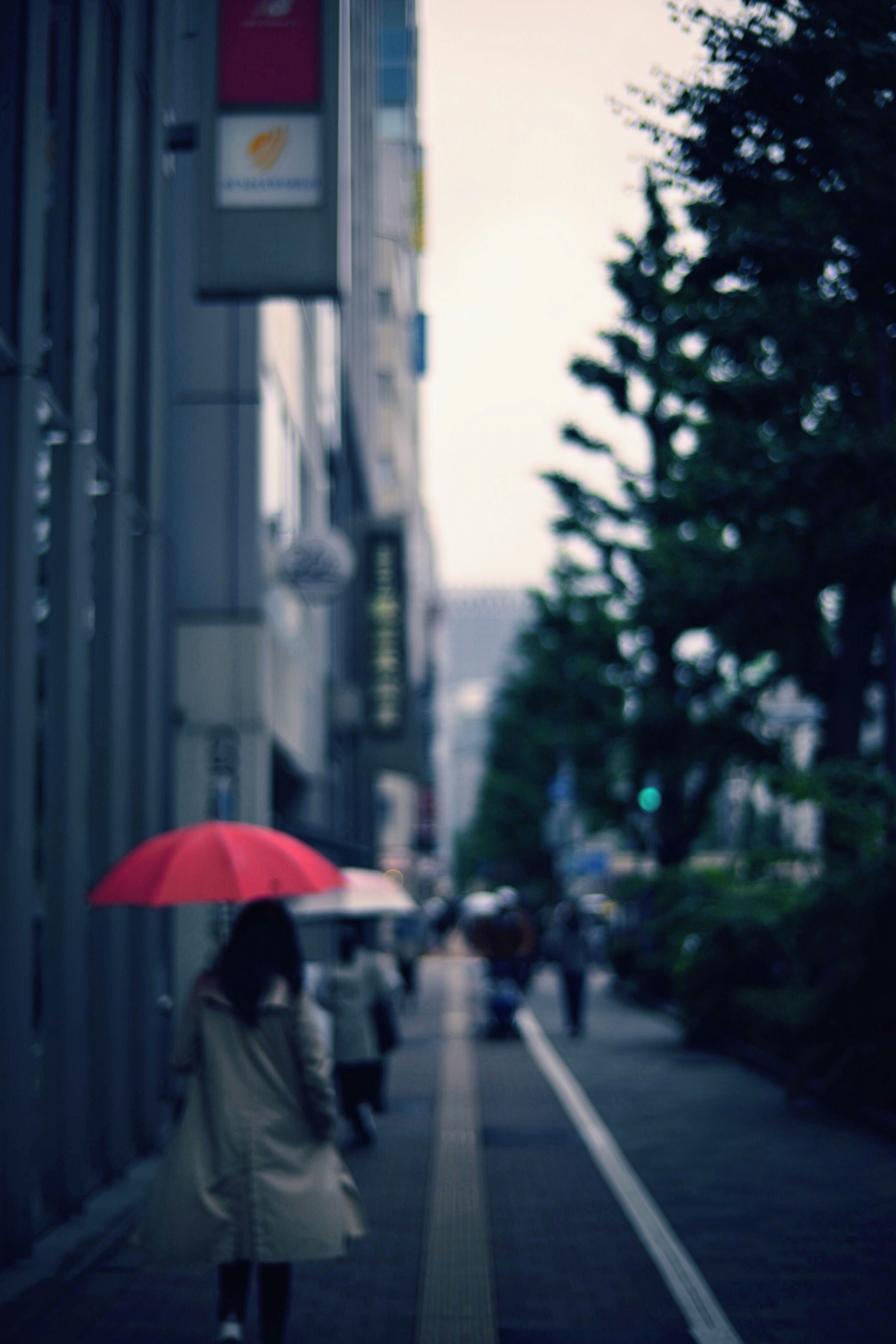 女人在城市环境中走路，手持红色雨伞