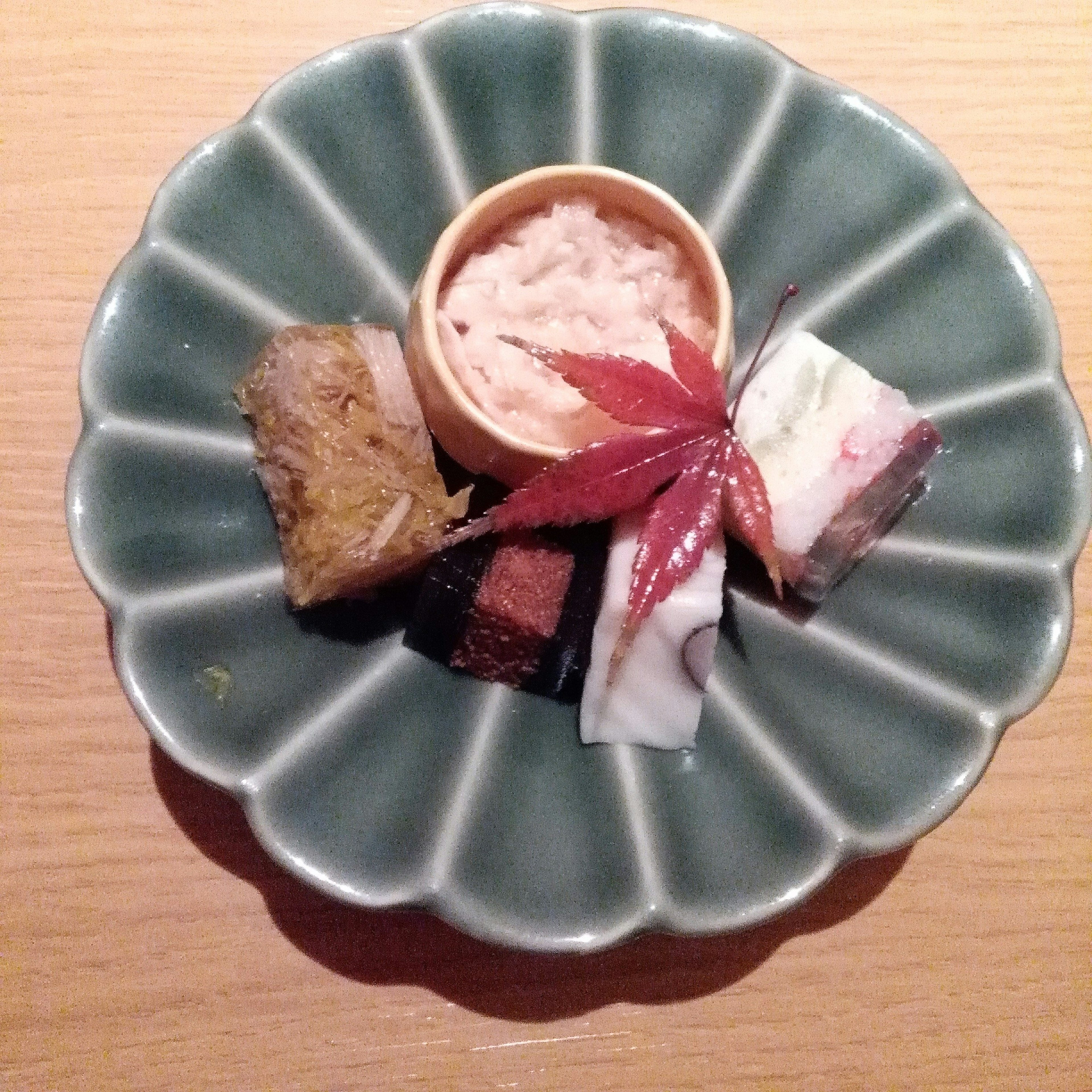 An assortment of Japanese appetizers arranged on a green plate