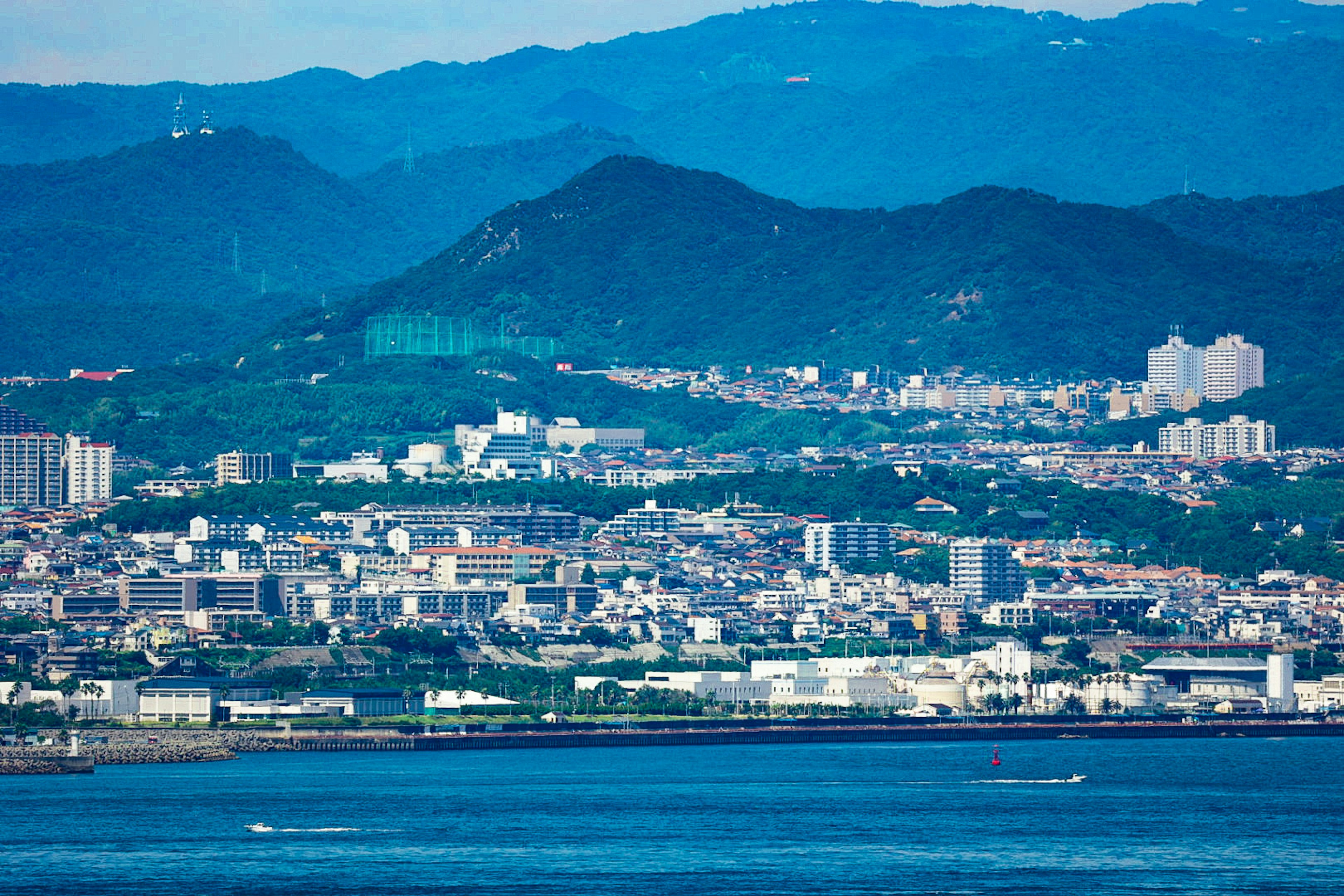 青い山々と海に囲まれた都市の風景