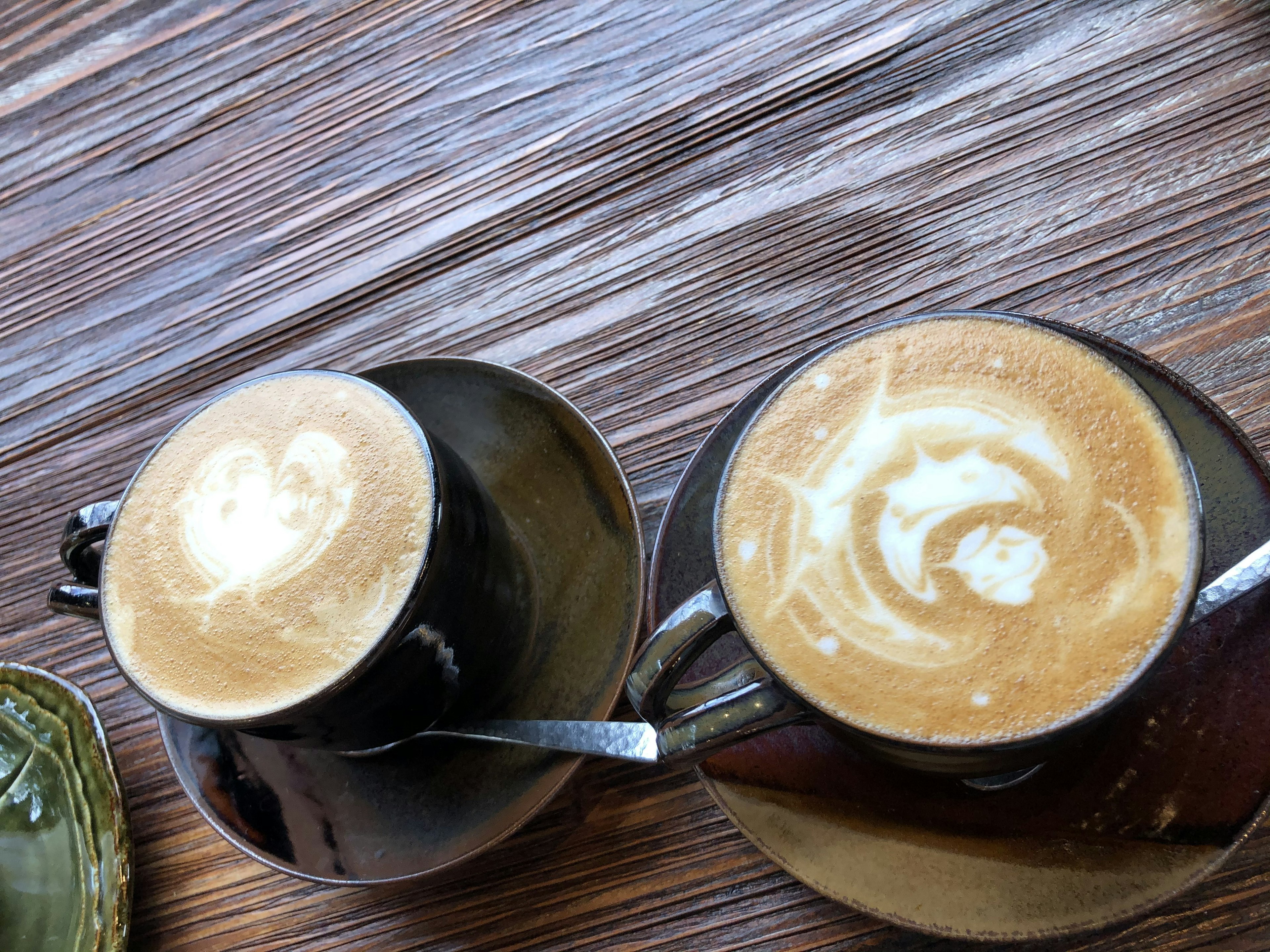 Two coffee cups with latte art on a wooden table