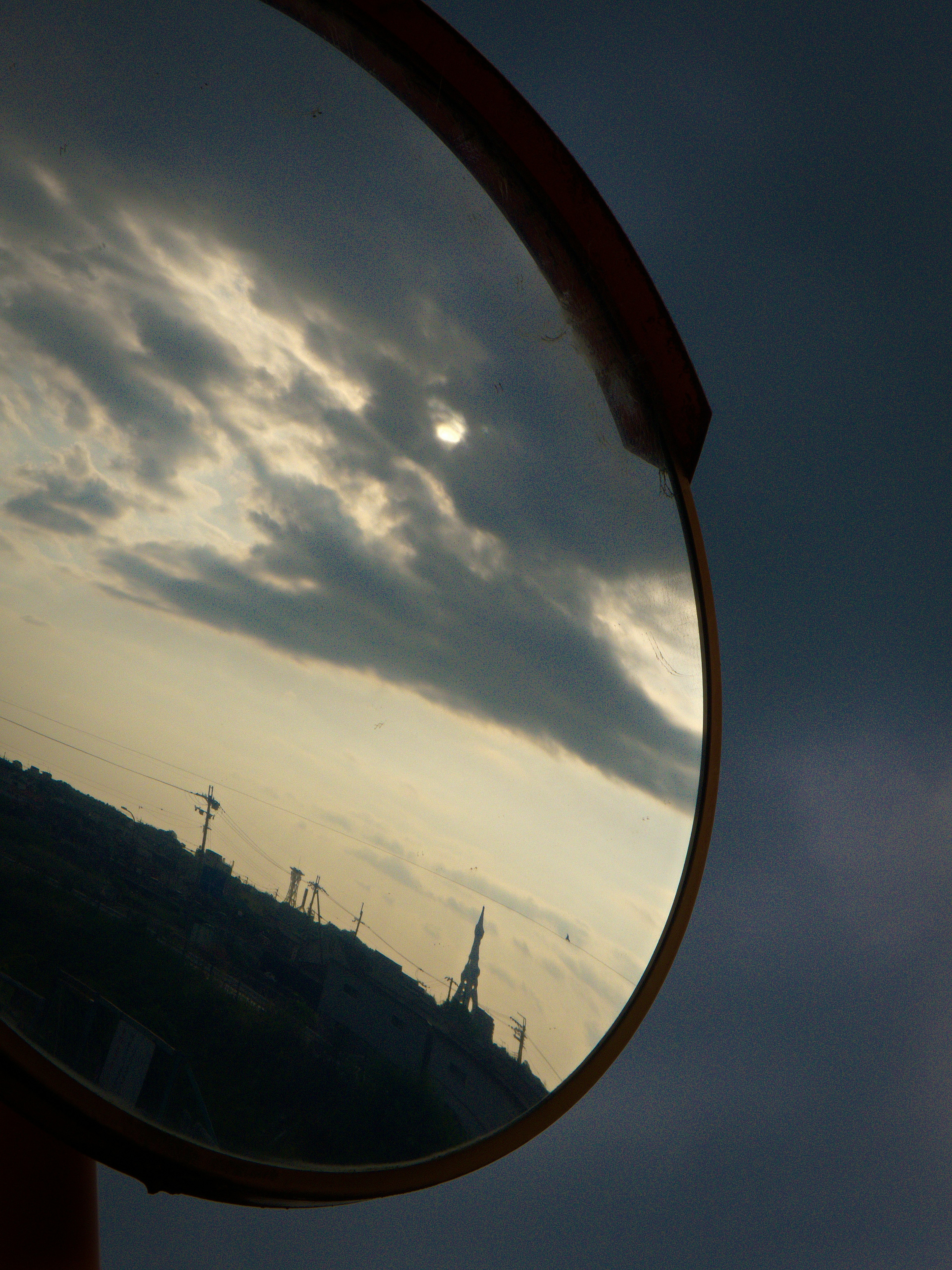 Landscape with clouds and sun reflected in a mirror