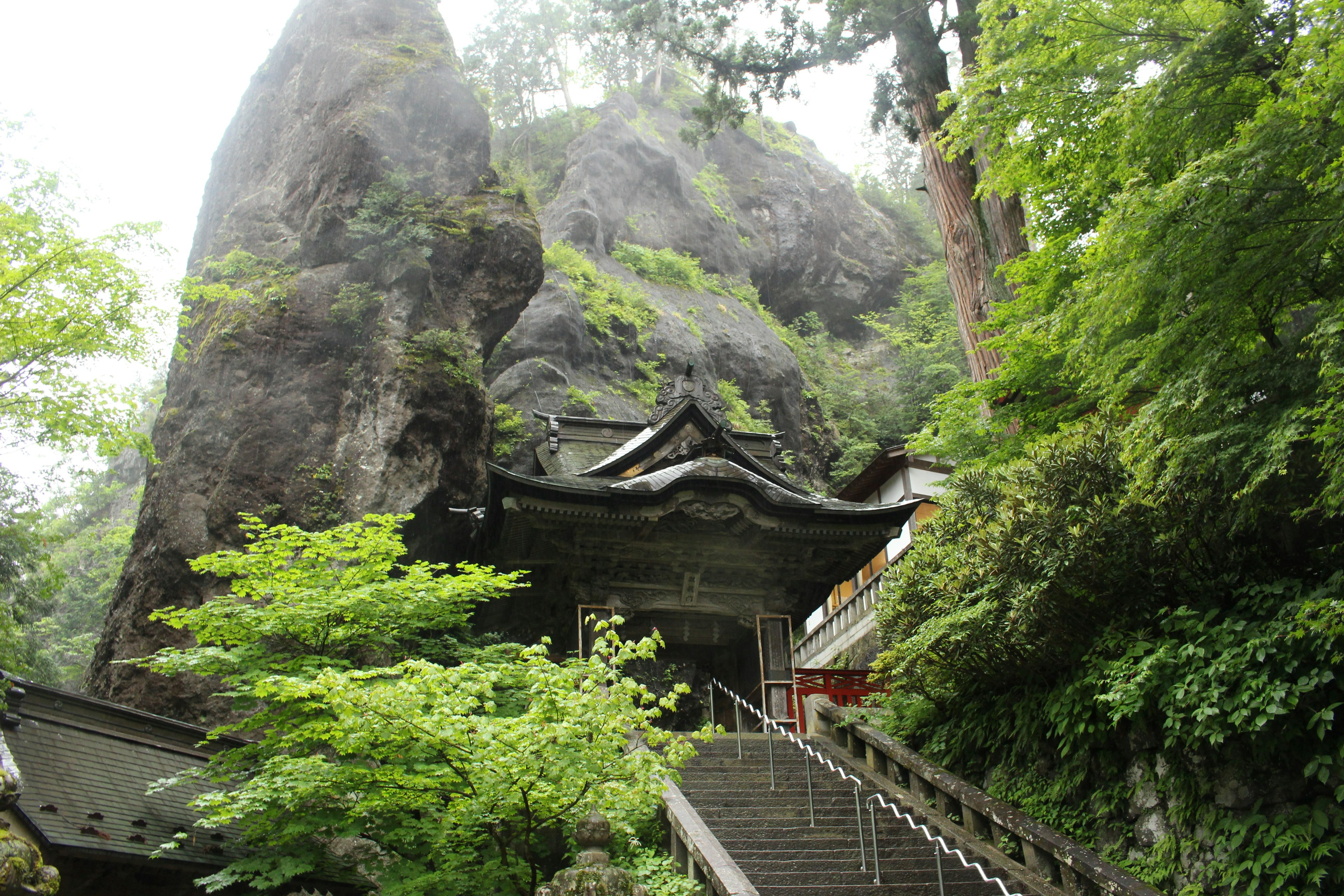 Entrée d'un sanctuaire entouré de grandes roches et d'une végétation luxuriante