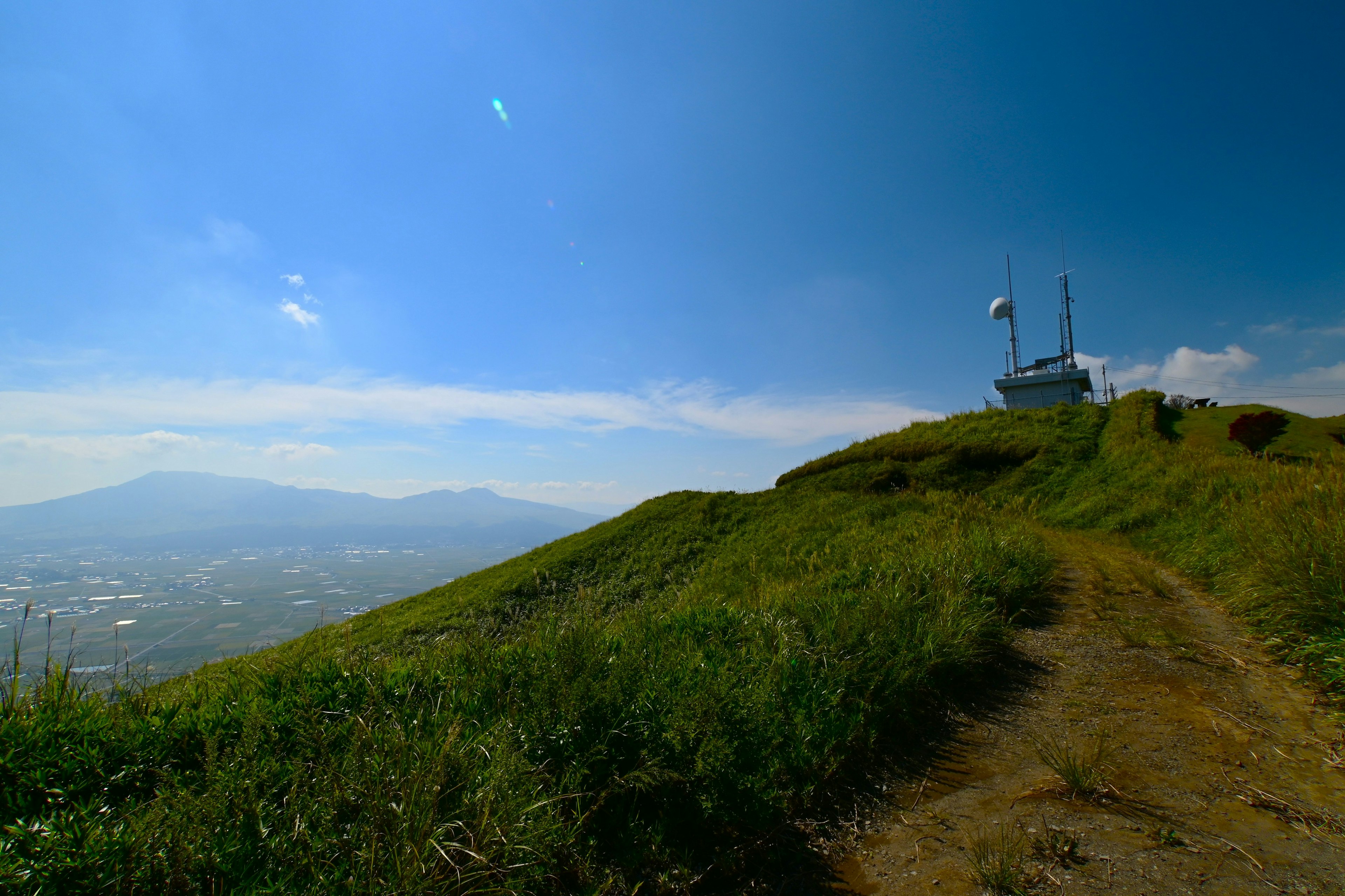 Scenic view of green hills under a blue sky with distant mountains