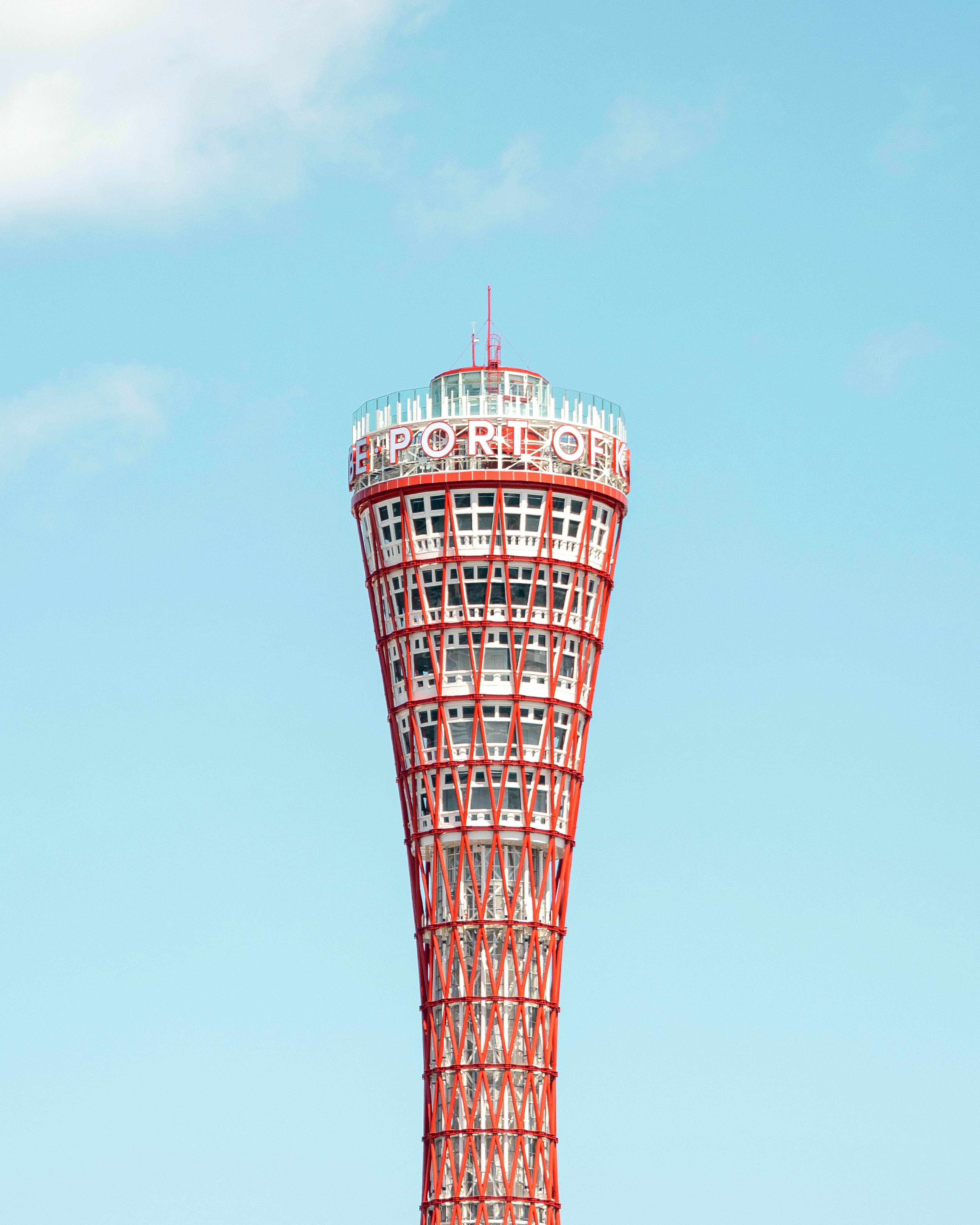 赤い色の神戸タワーが青空の下にそびえ立つ