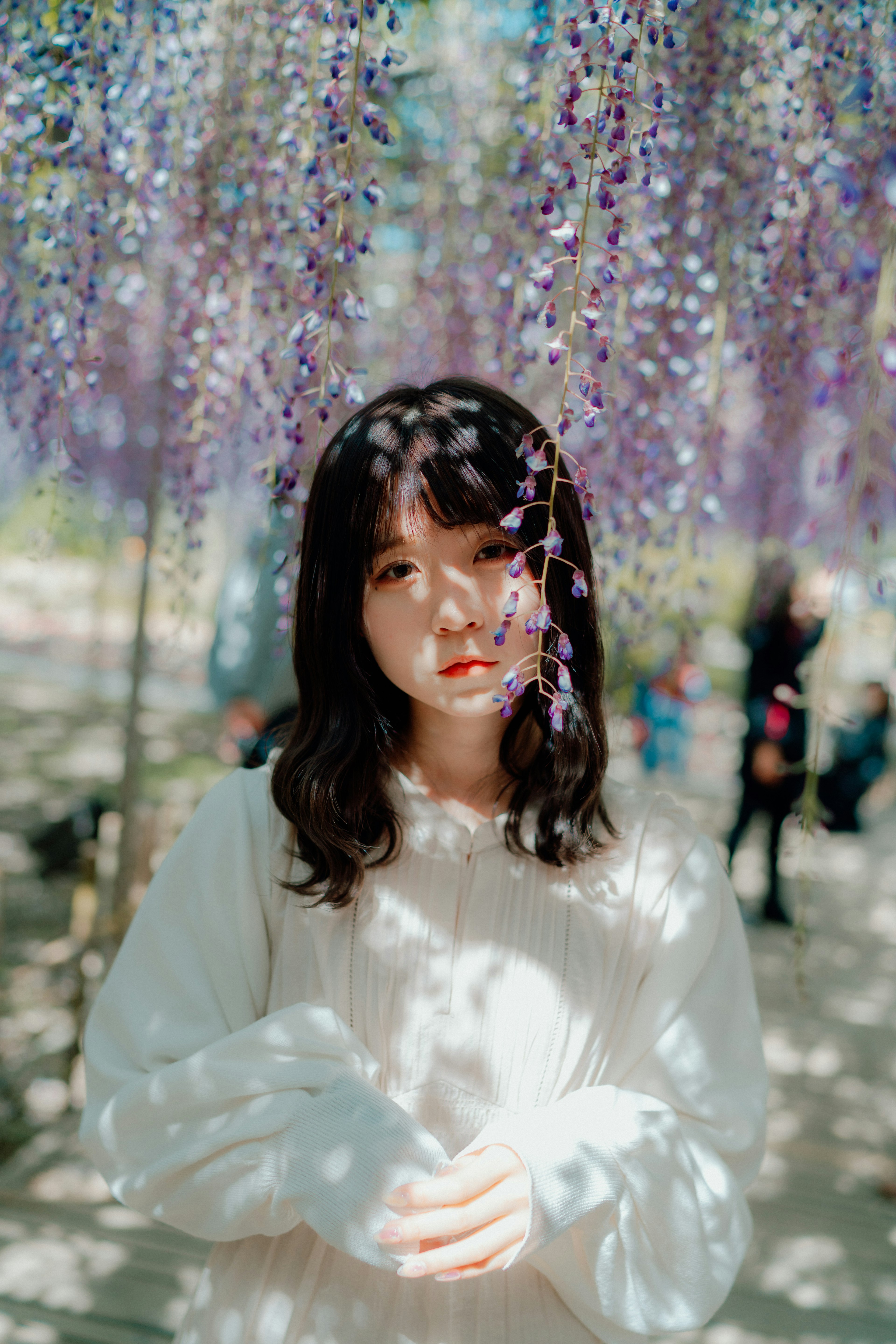 紫色の花の下に立つ女性のポートレート