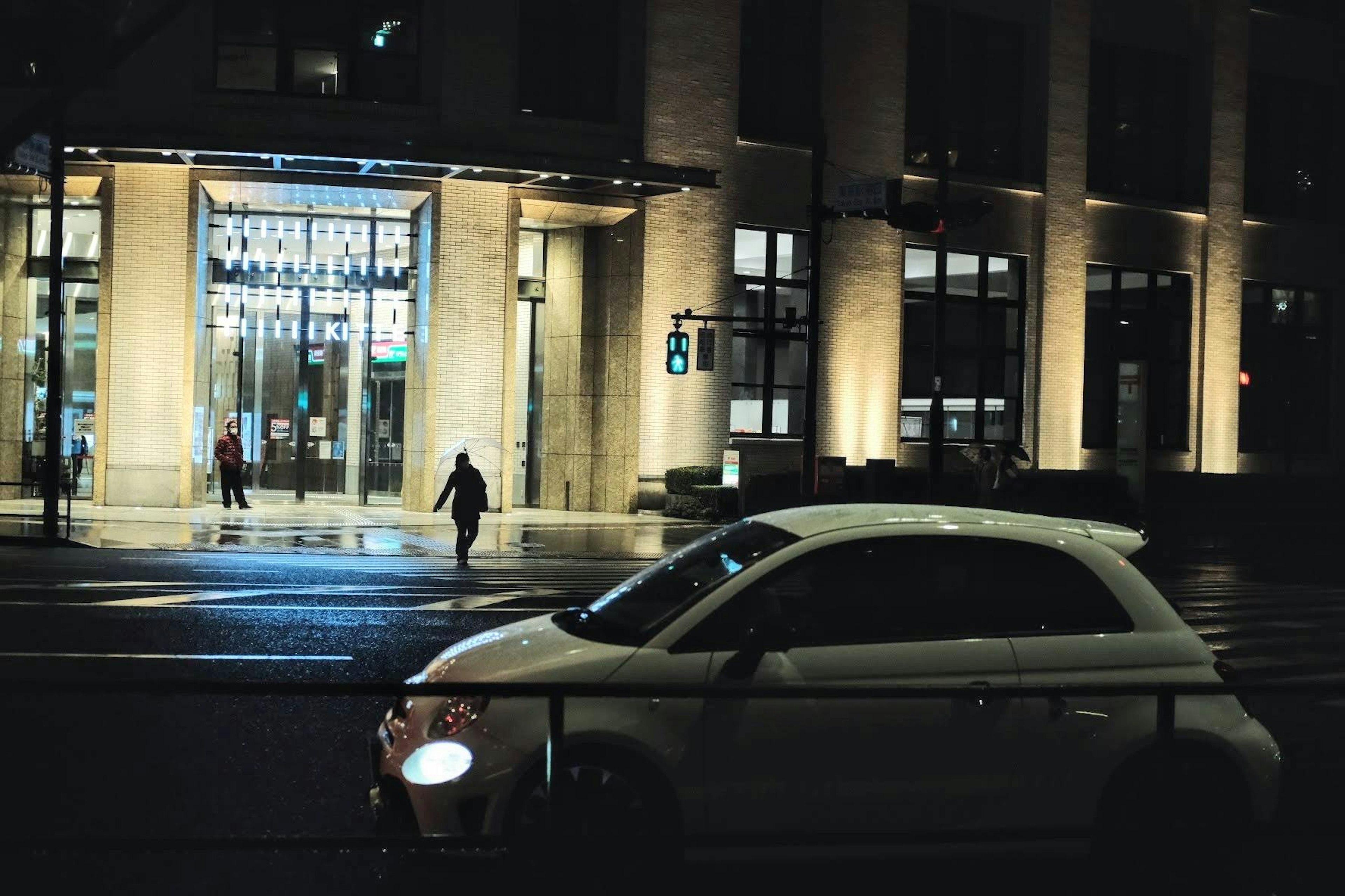 夜景の街並みに停車した白い車と明るく照らされた建物