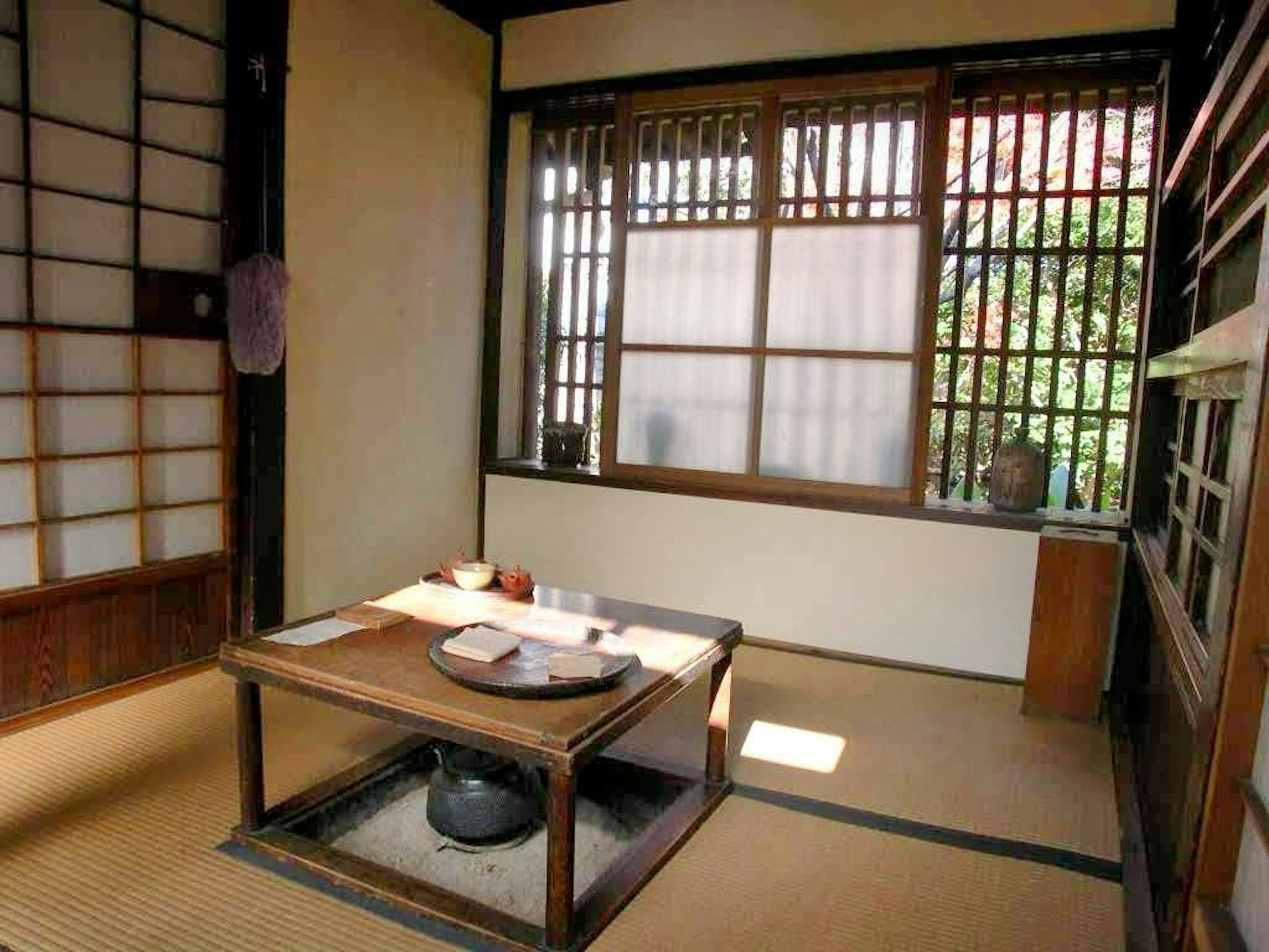 Simple interior of a Japanese room with a table and cushions, natural light streaming through the window