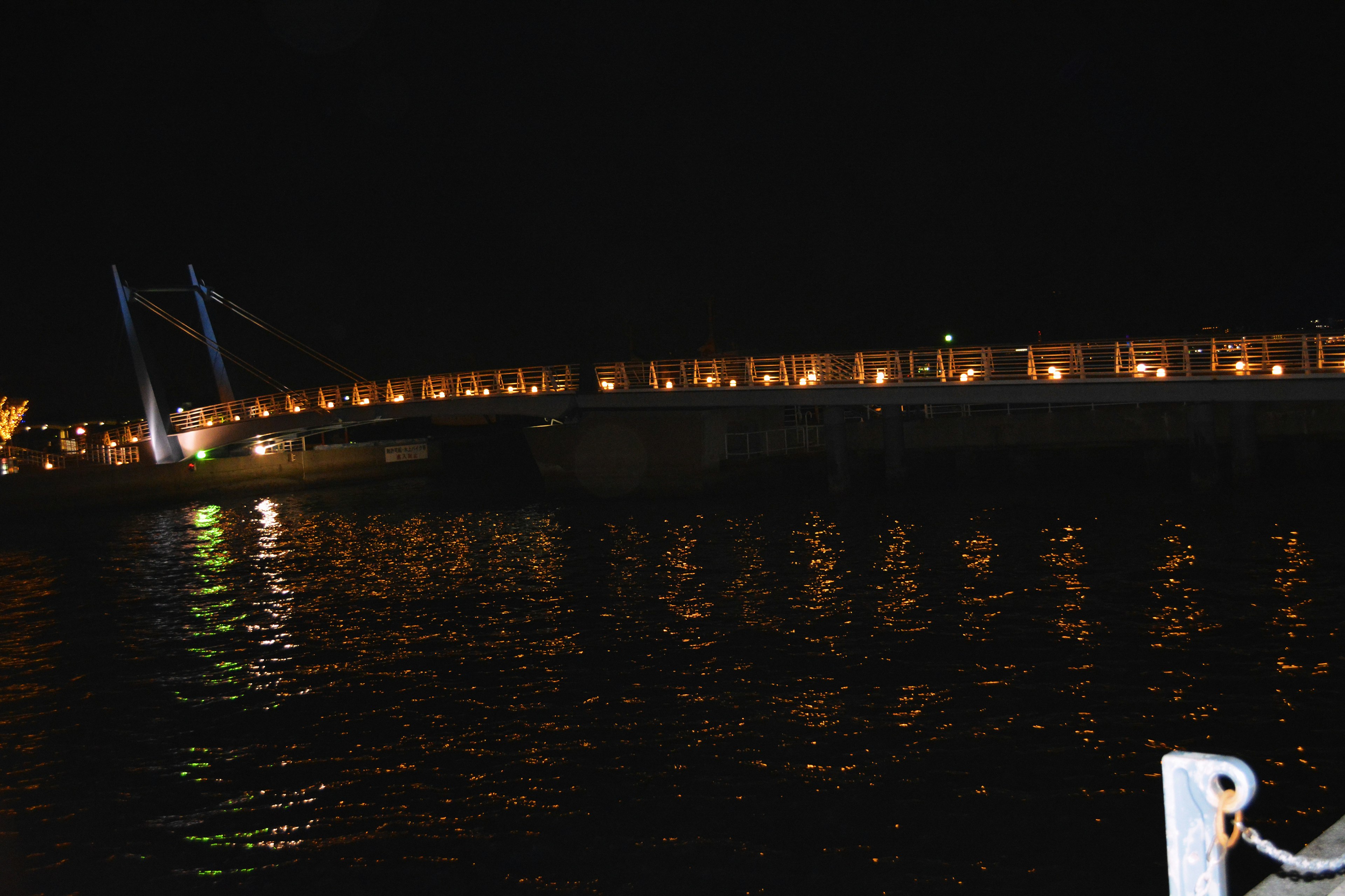 Ponte luminoso che si riflette sul fiume di notte con luci circostanti