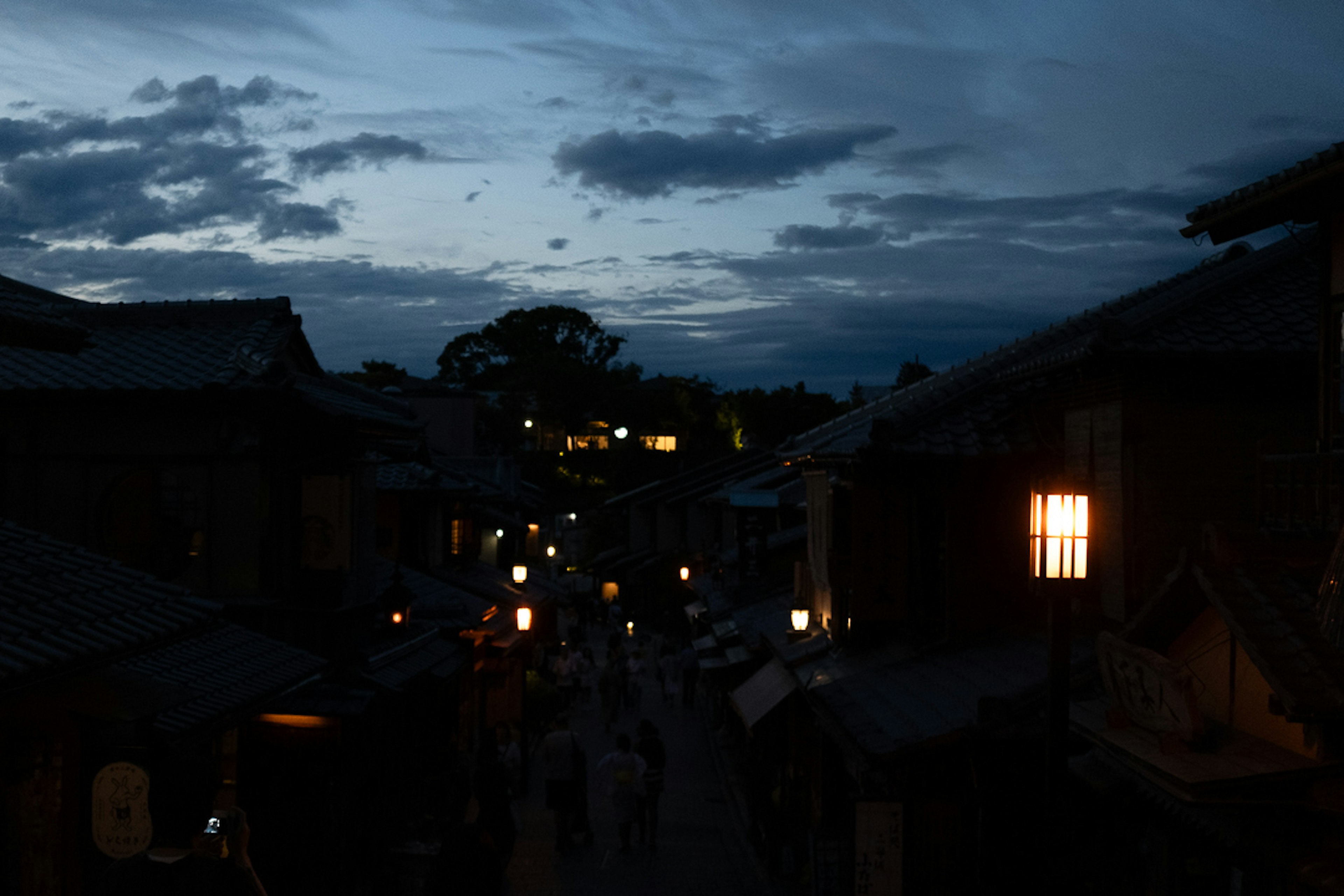 Scène de rue au crépuscule avec des lanternes et un ciel nuageux