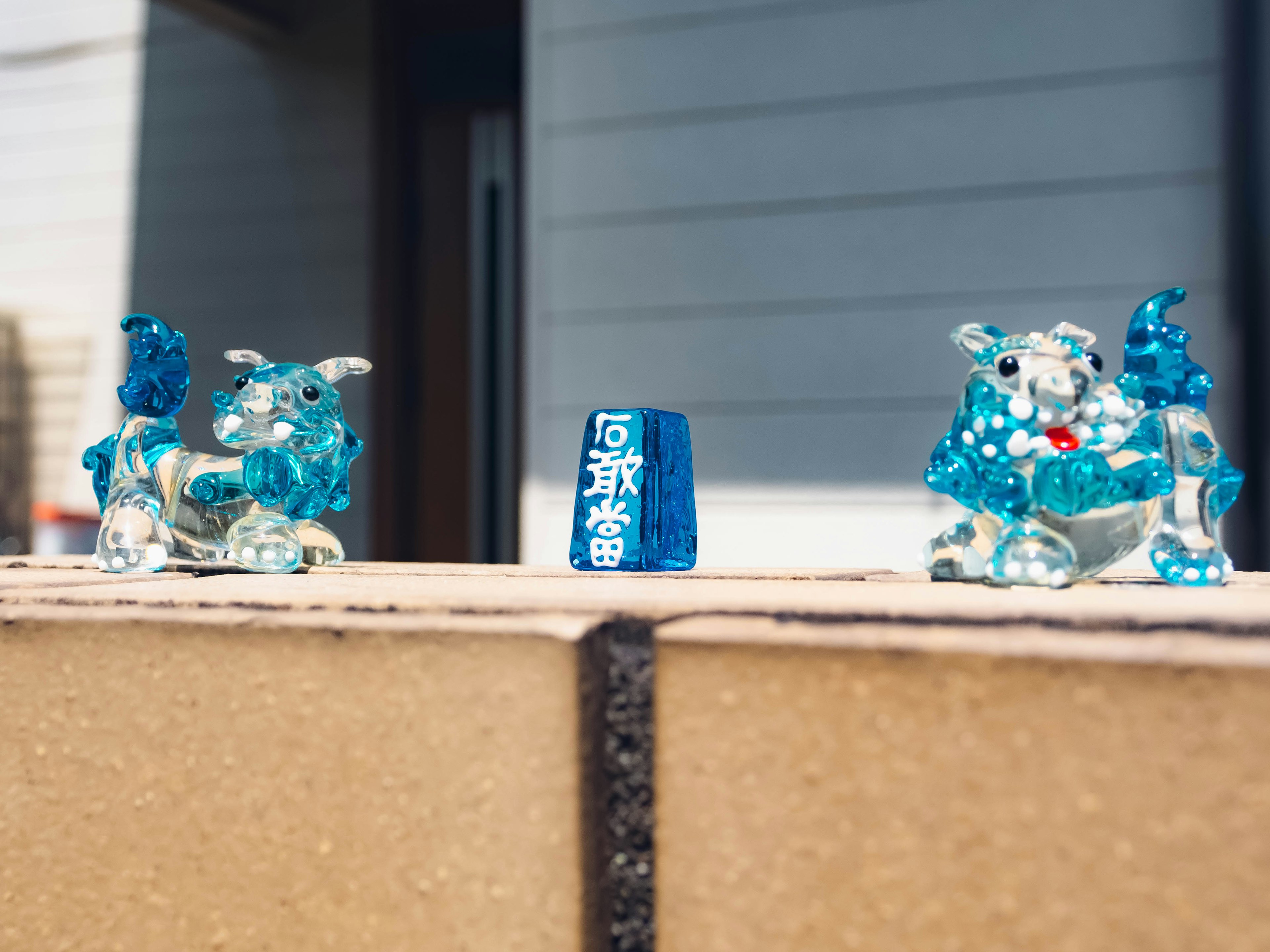 Two blue glass lion figurines and a blue stone placed on a ledge