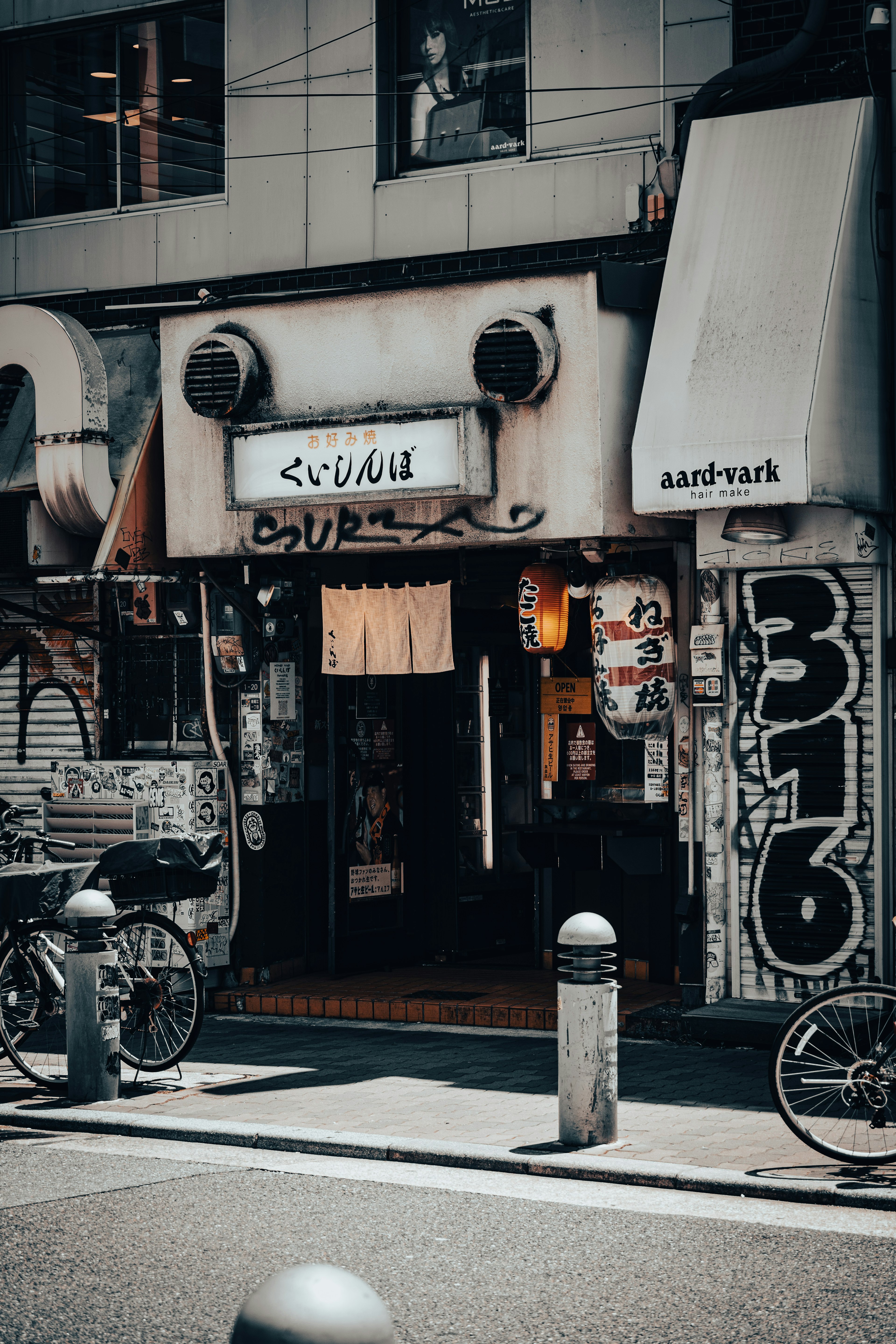 Exterior of an old Japanese eatery with a visible entrance and a person inside bicycles parked nearby