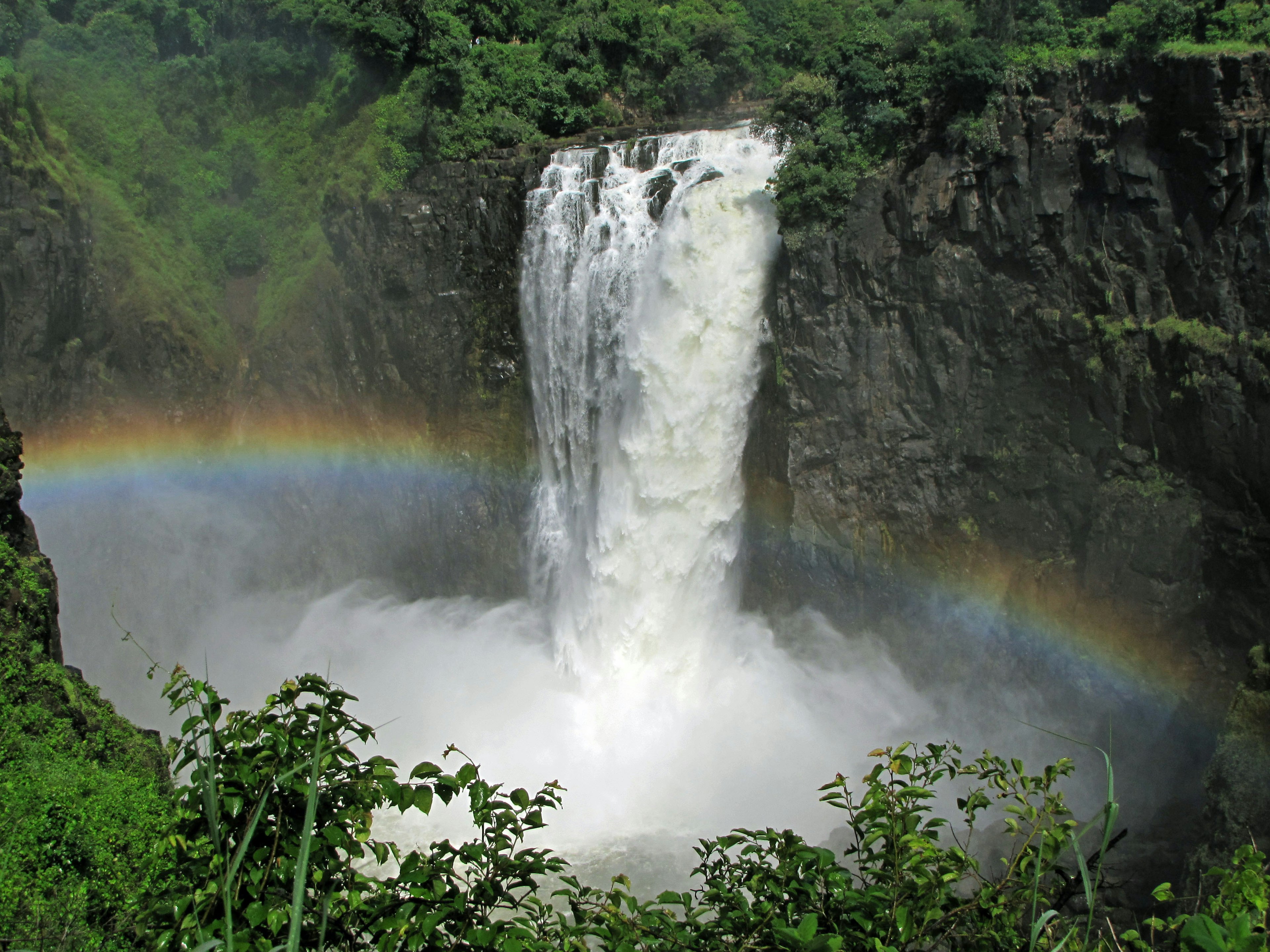 Une magnifique cascade avec un arc-en-ciel visible