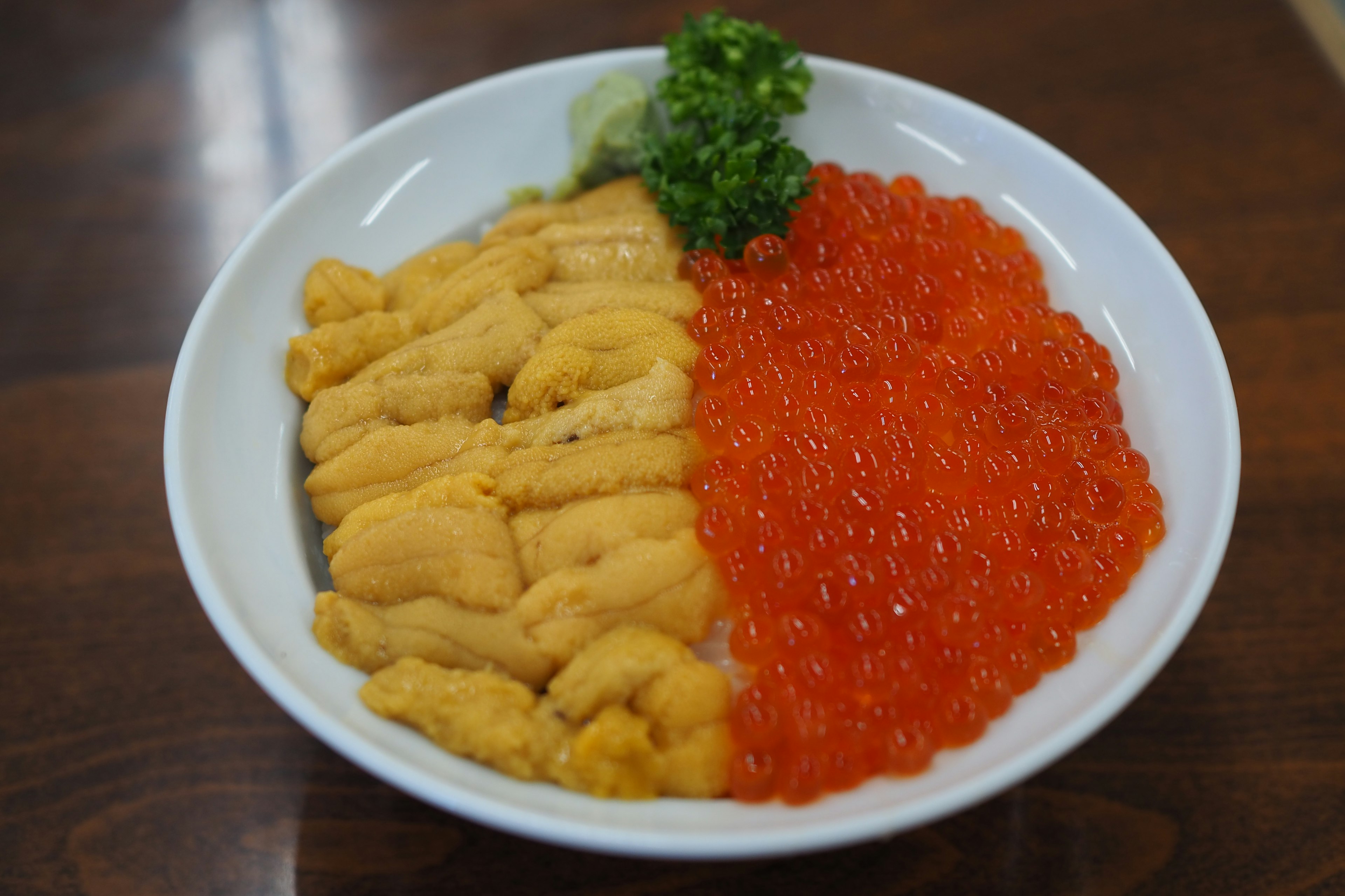 Bowl of uni and ikura garnished with green onion