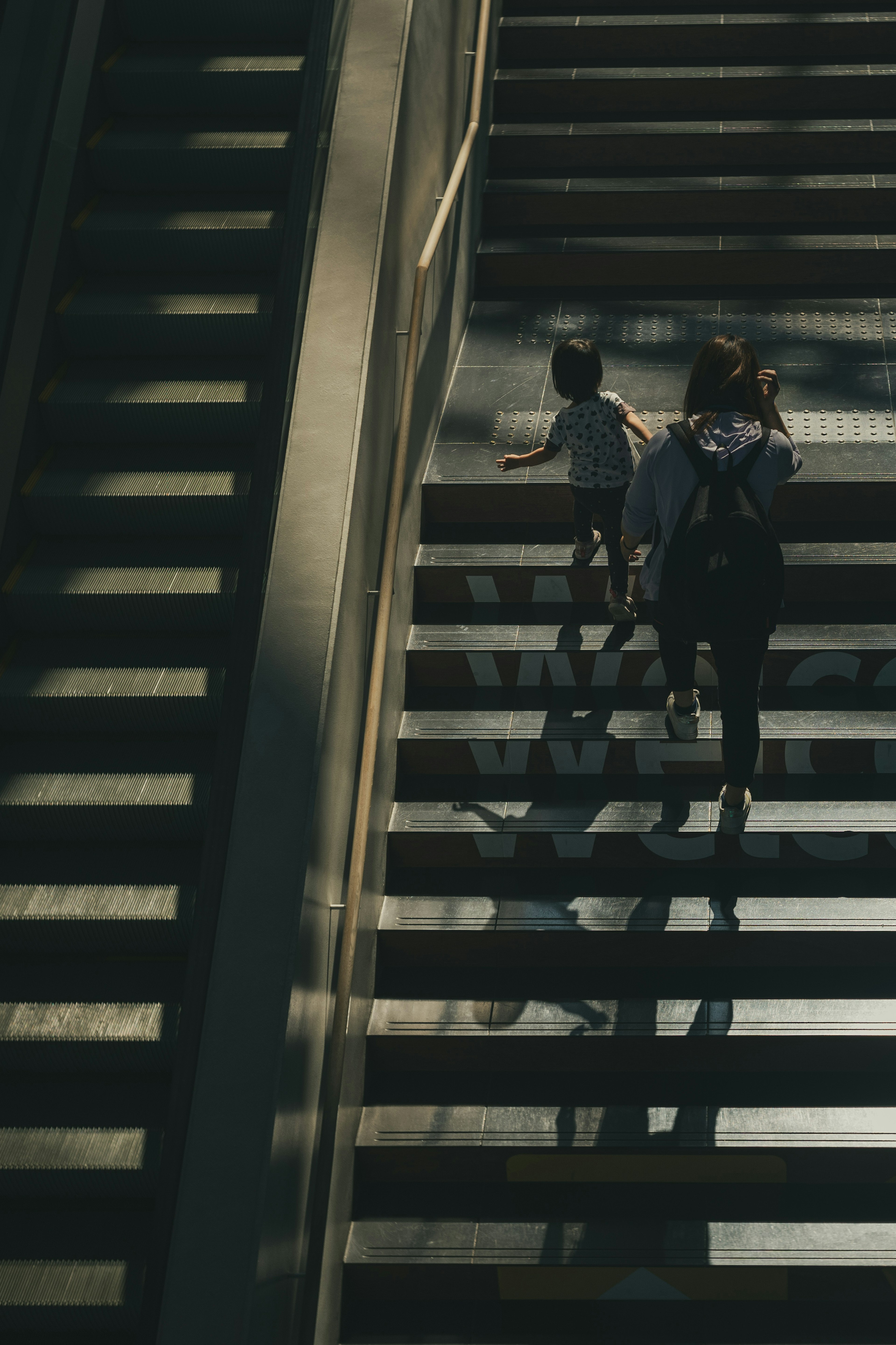 A parent and child walking up a staircase in soft lighting