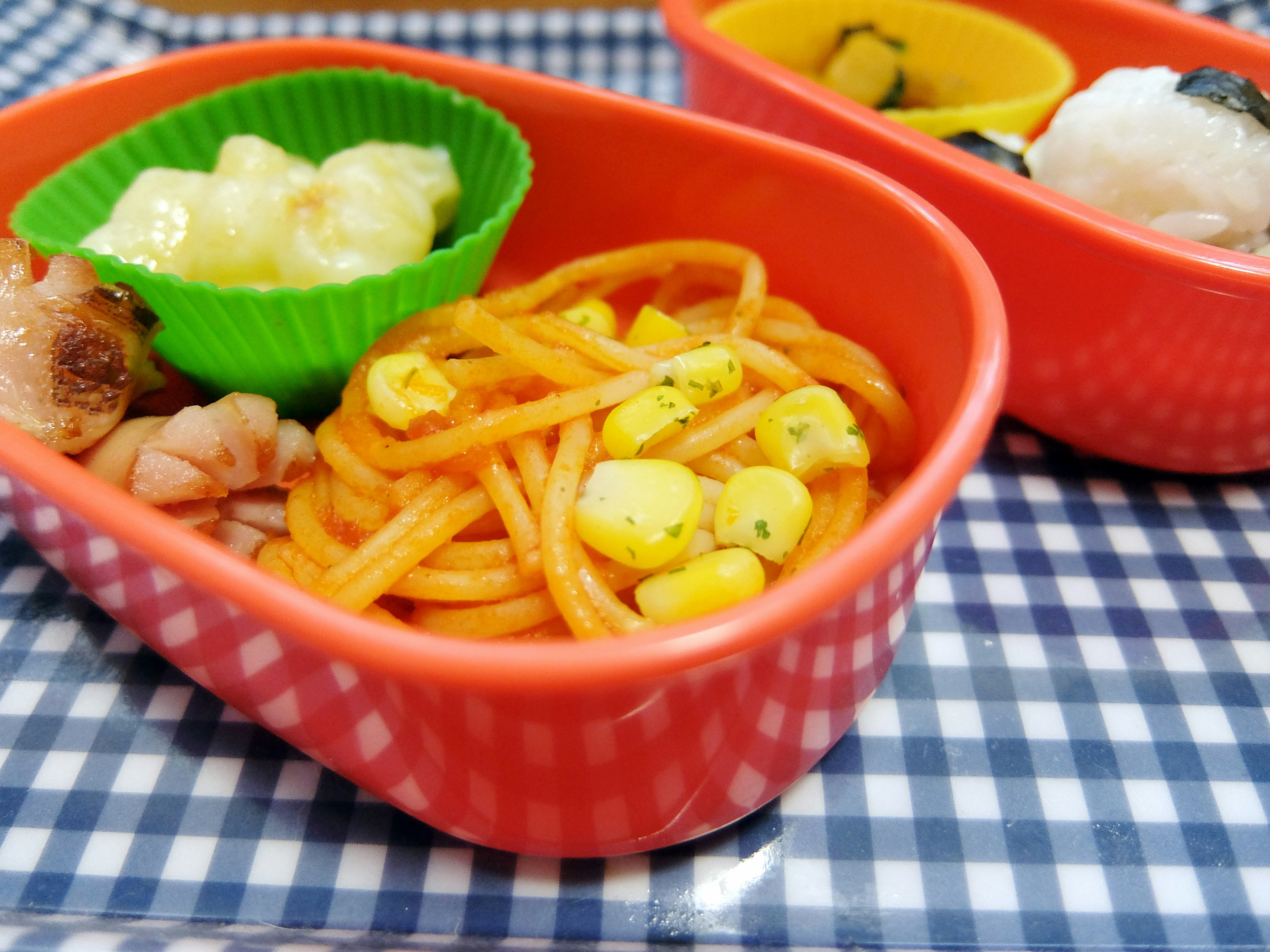 Scatola bento rossa con spaghetti e verdure disposti per un pasto equilibrato