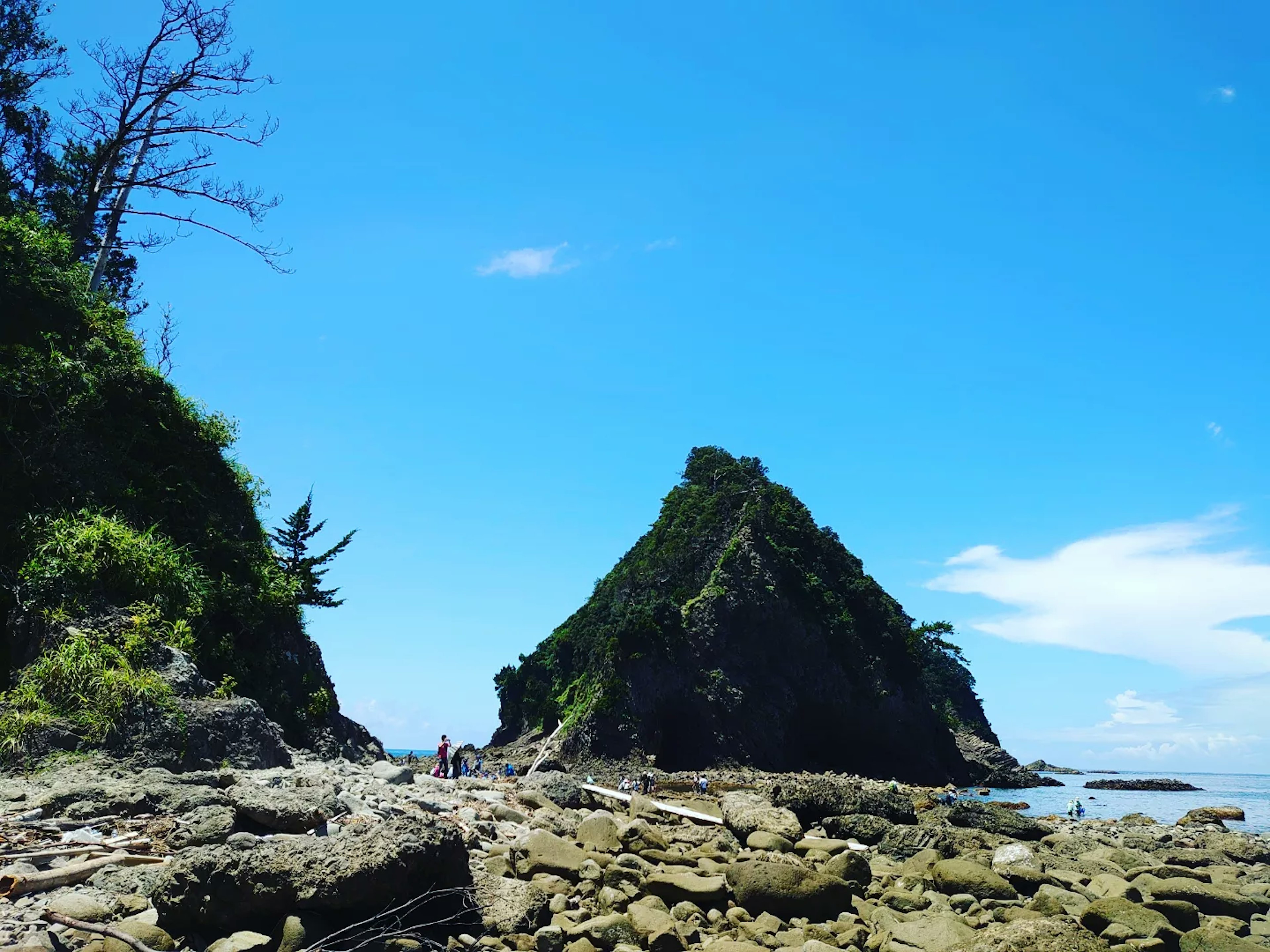 Coastal landscape with a pointed mountain under a clear blue sky