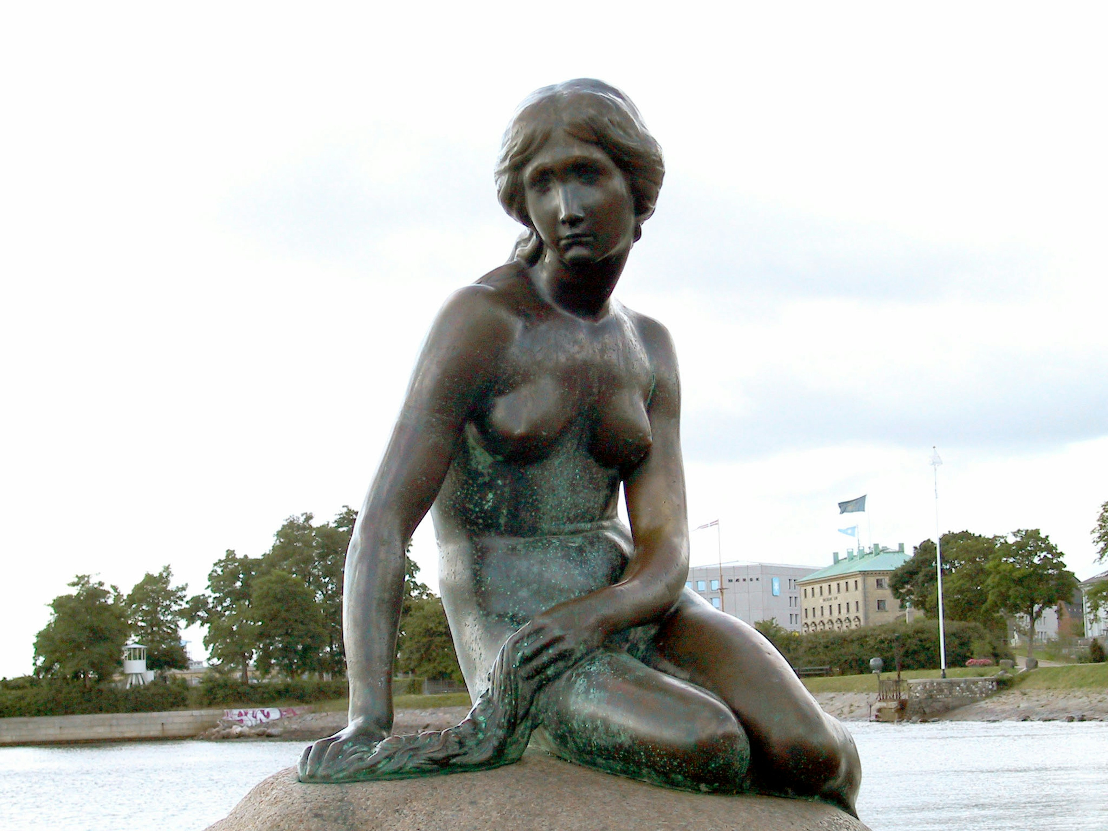 Estatua de bronce de una sirena sentada sobre una roca