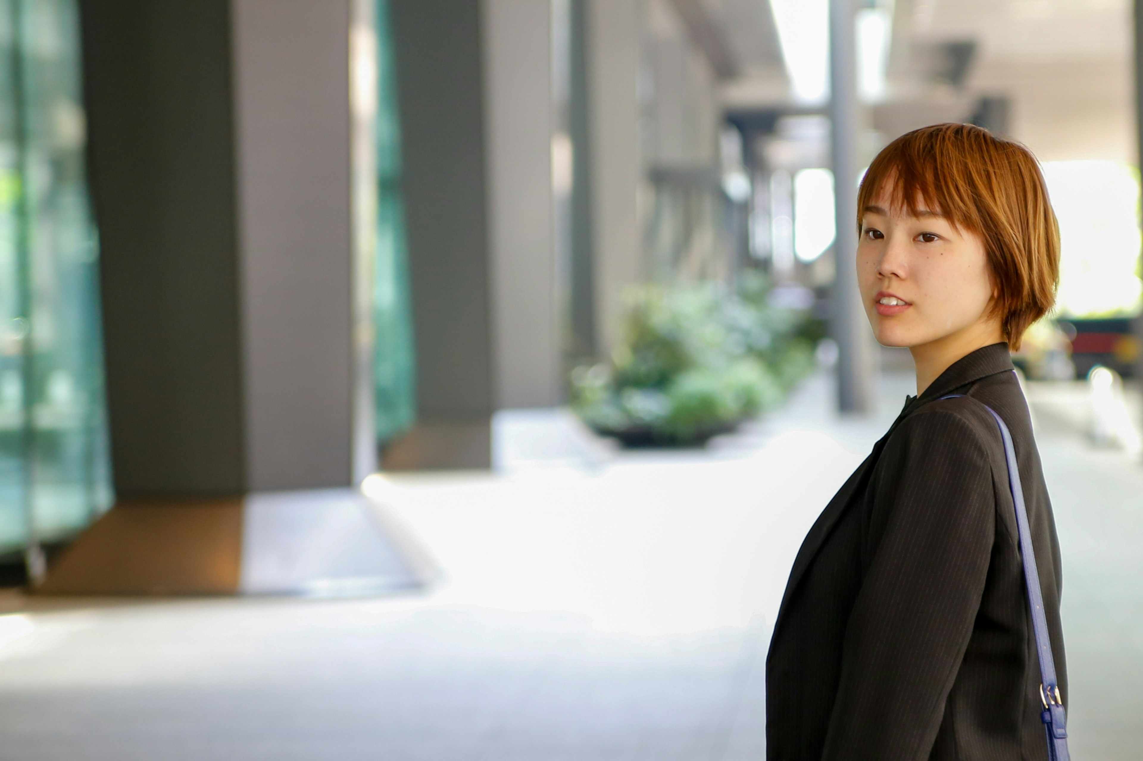 A woman in business casual attire looking back outdoors