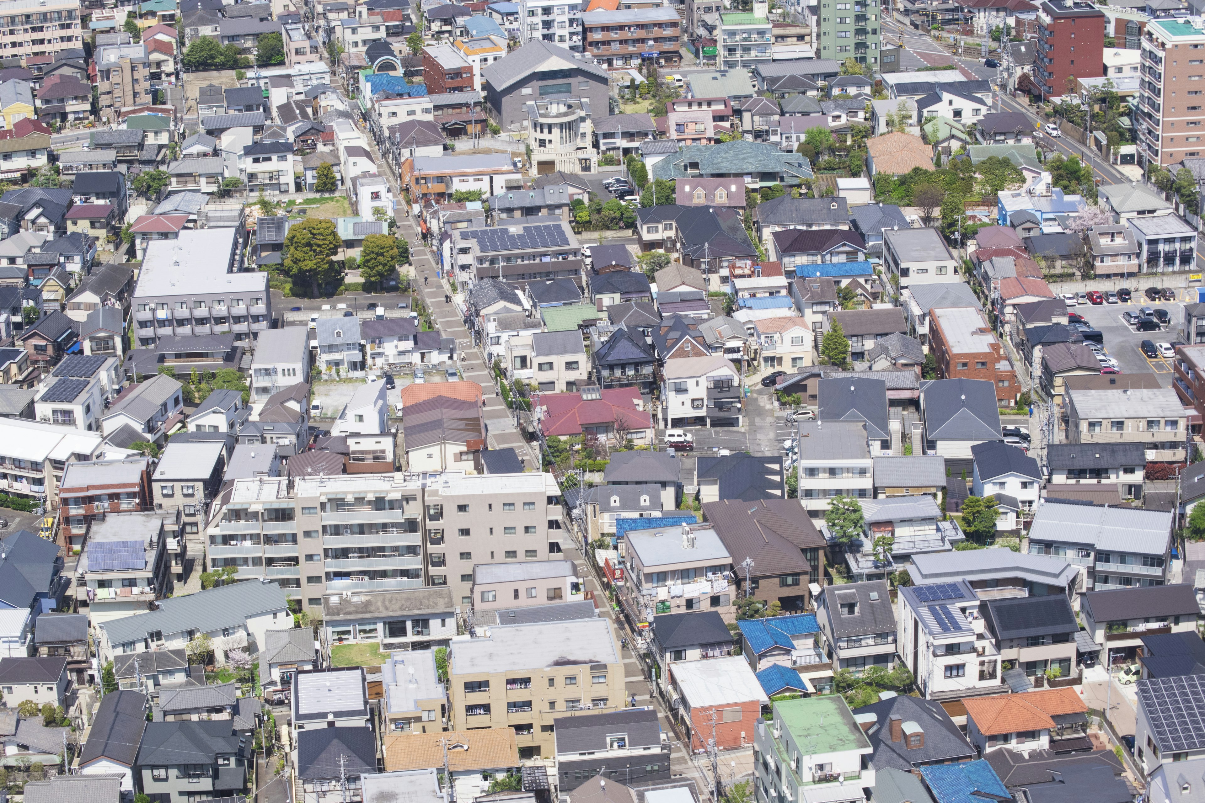 Aerial view of an urban residential area featuring densely packed houses with tiled roofs and various colors