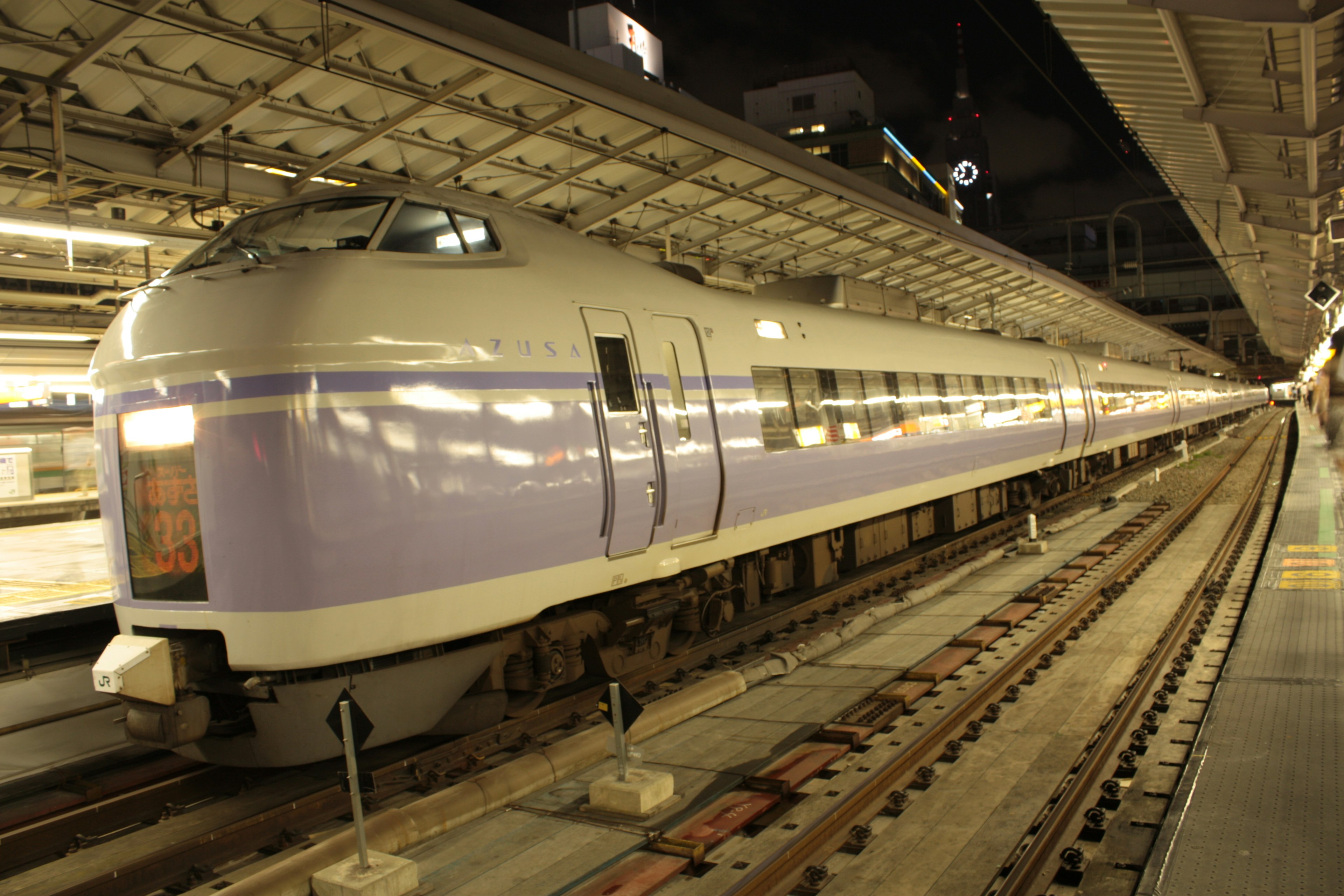 Lila Shinkansen-Zug, der an einem Nachtbahnhof hält