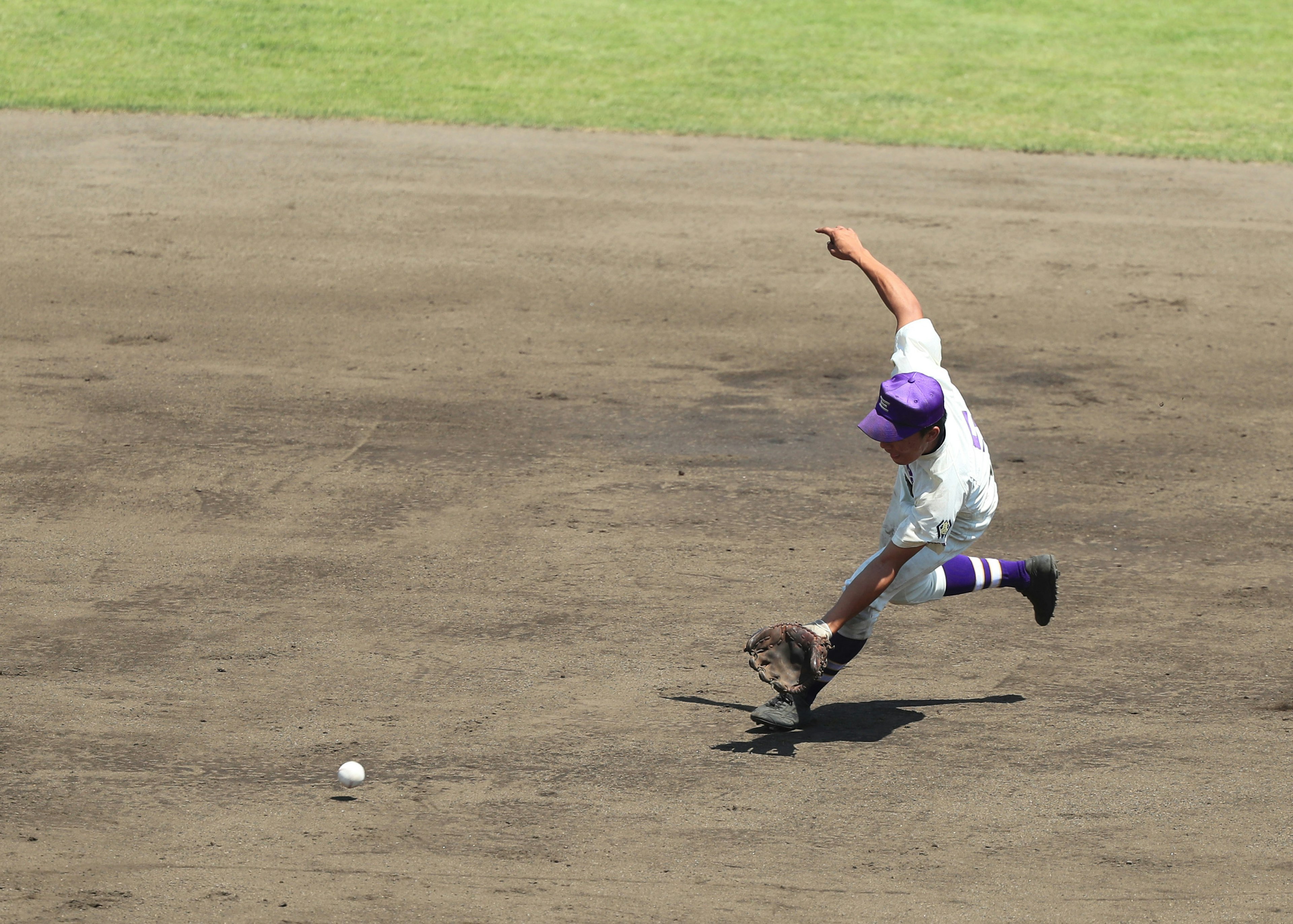 Niño persiguiendo una pelota en un campo de béisbol