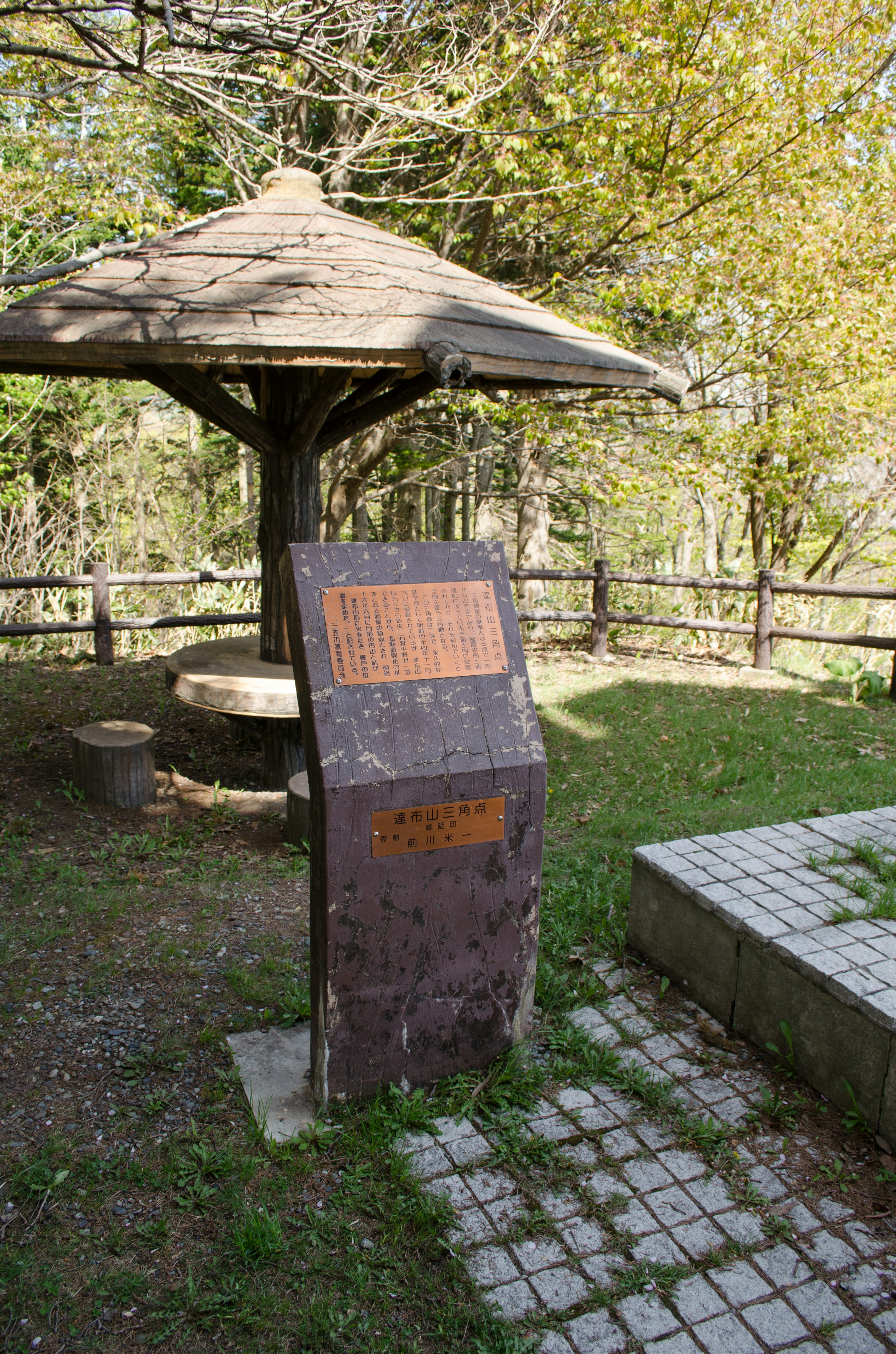 Pabellón de madera y cartel informativo en un área verde del parque