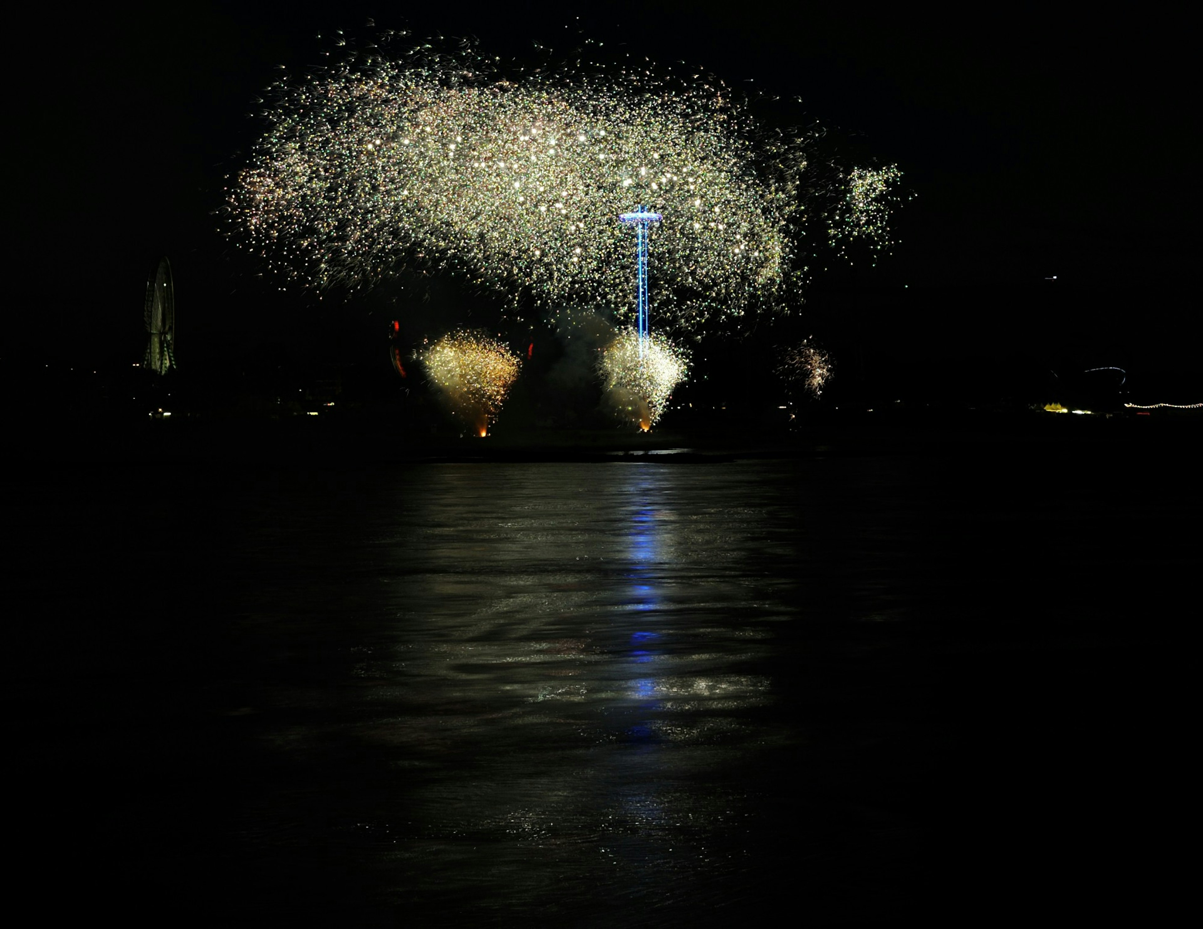 Feux d'artifice illuminant le ciel nocturne avec des reflets sur l'eau