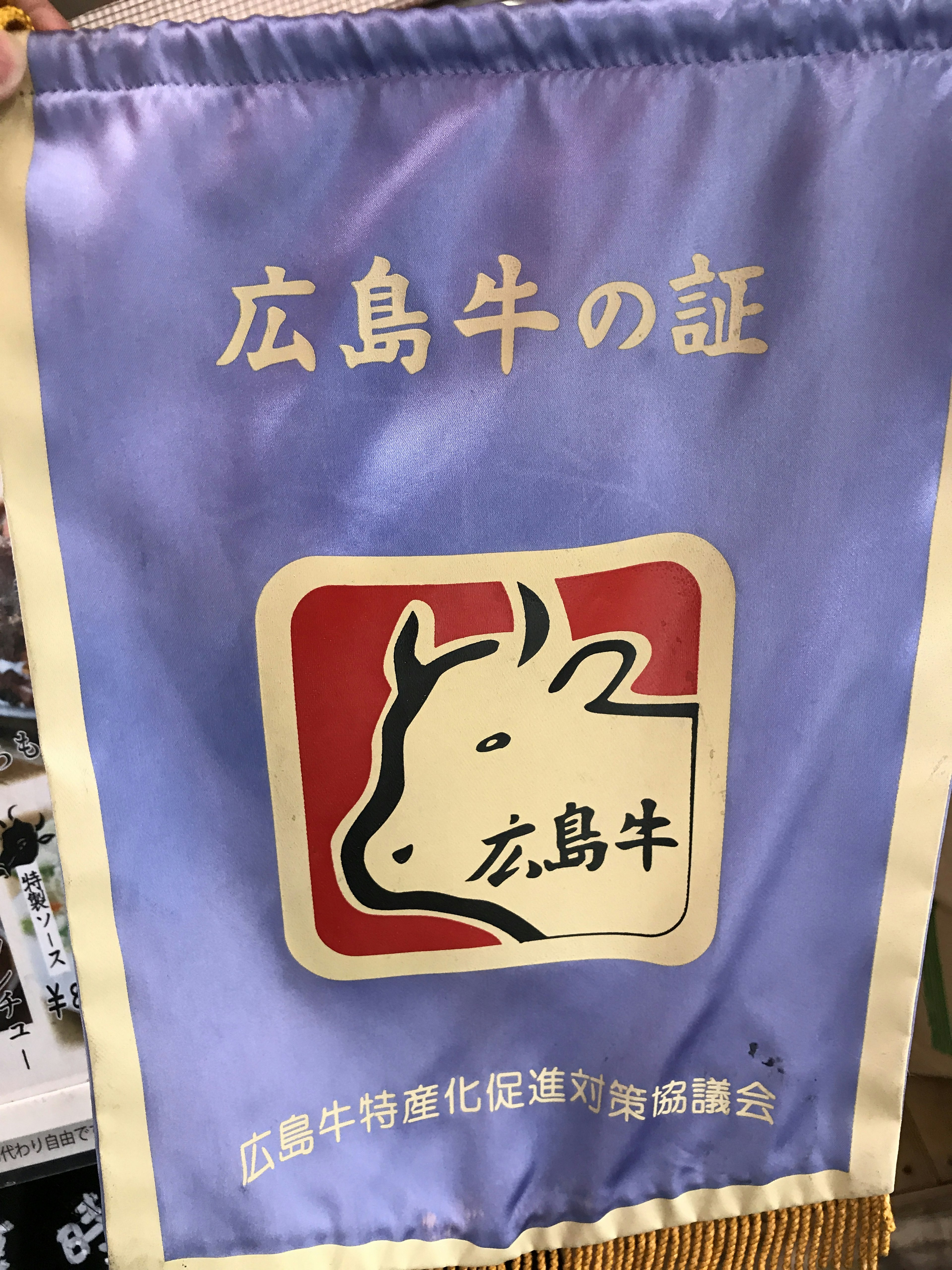 Flag representing Hiroshima beef with a purple background and a white cow logo