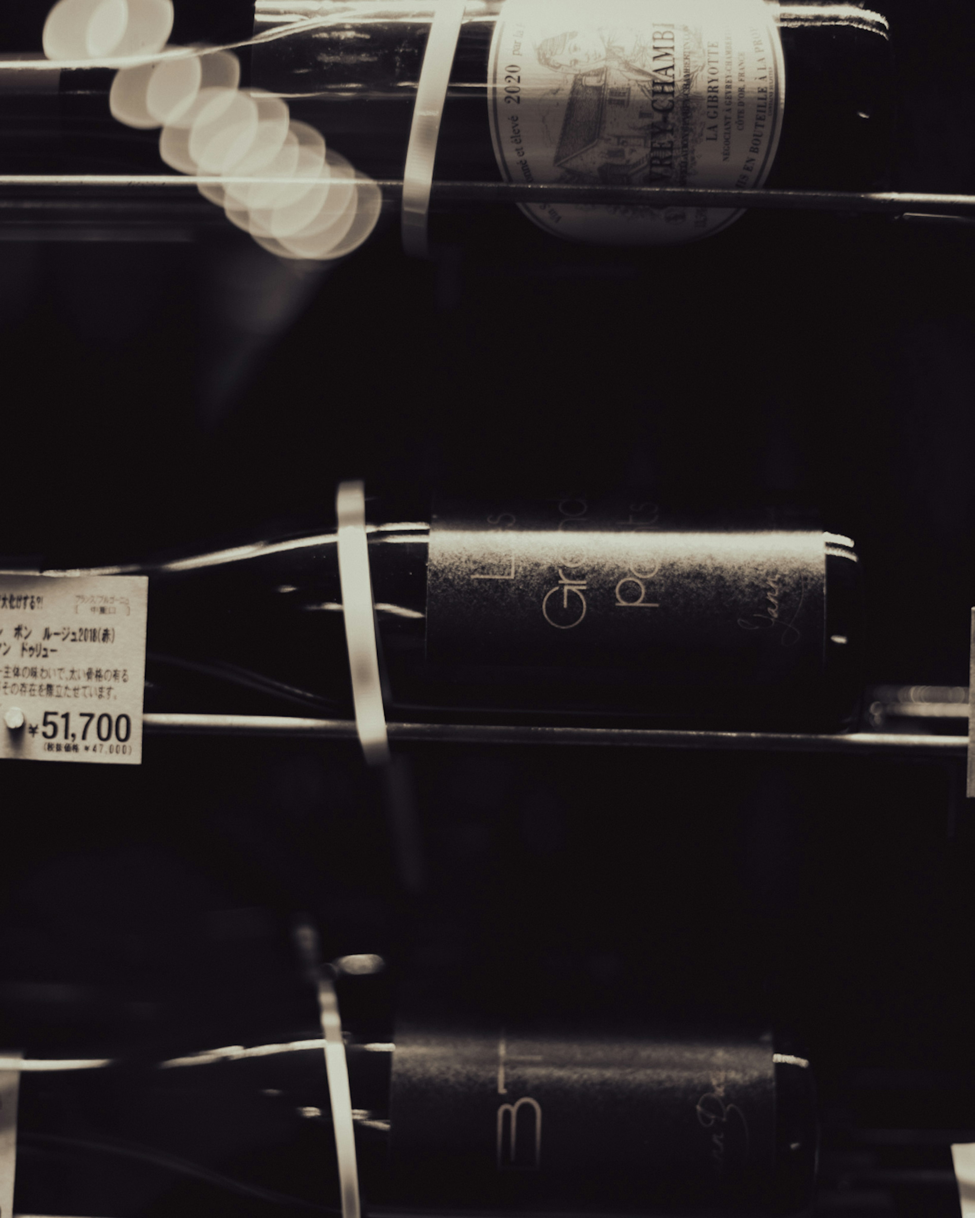 Image of wine bottles arranged against a black background with visible labels and price tags