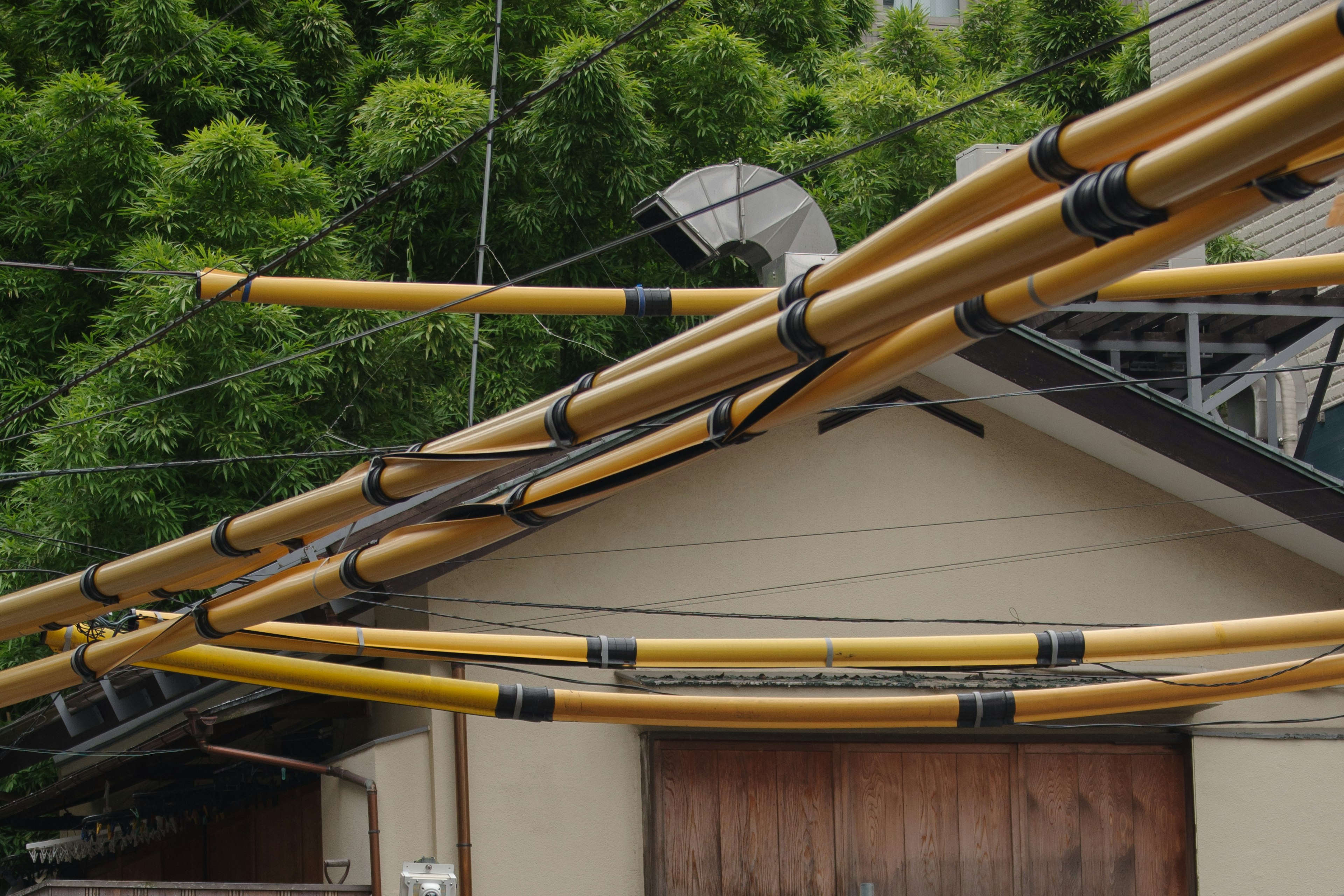 A view of a house with yellow pipes lying on the roof green trees in the background