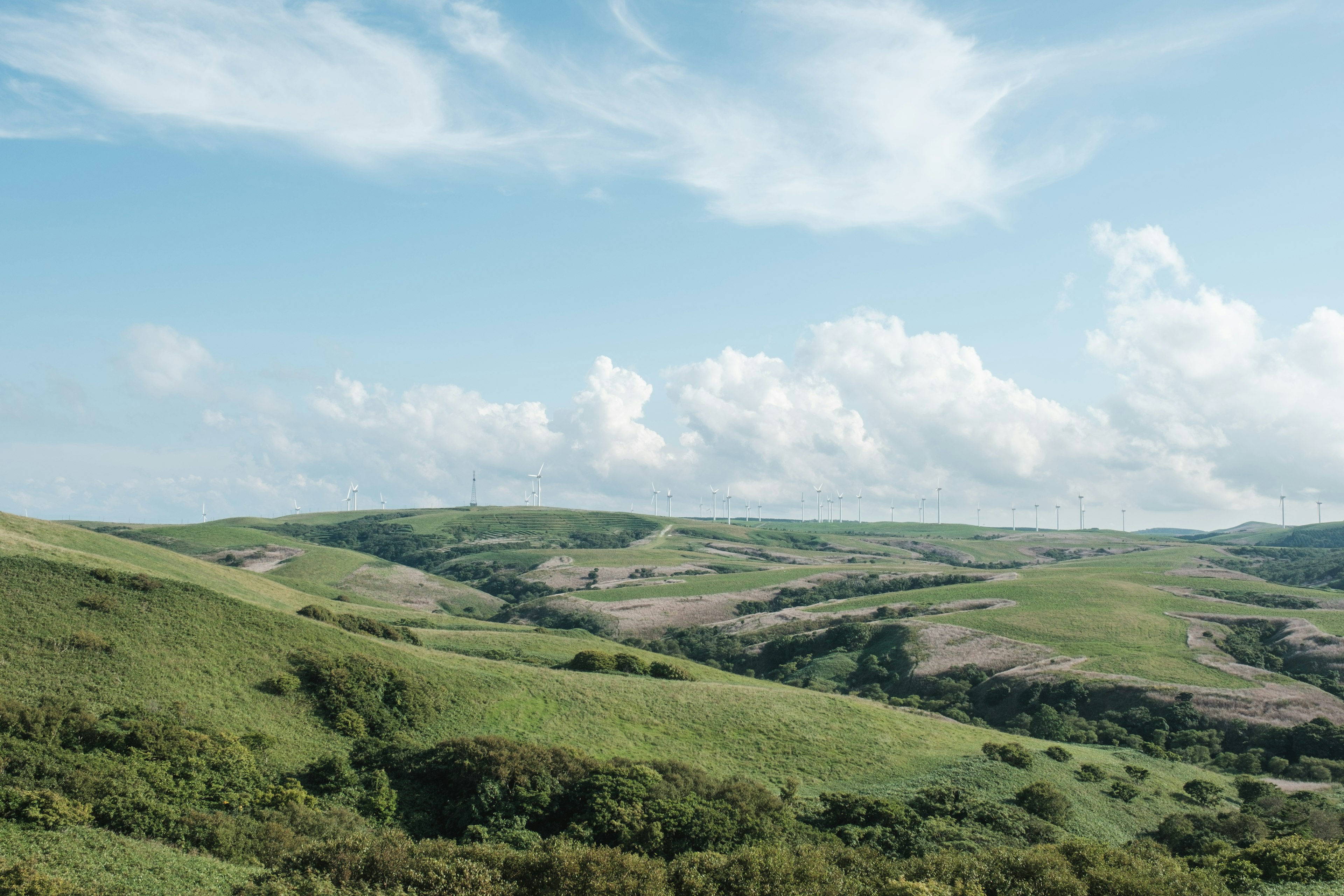 Una vista panoramica di colline verdi ondulate sotto un cielo azzurro con nuvole bianche